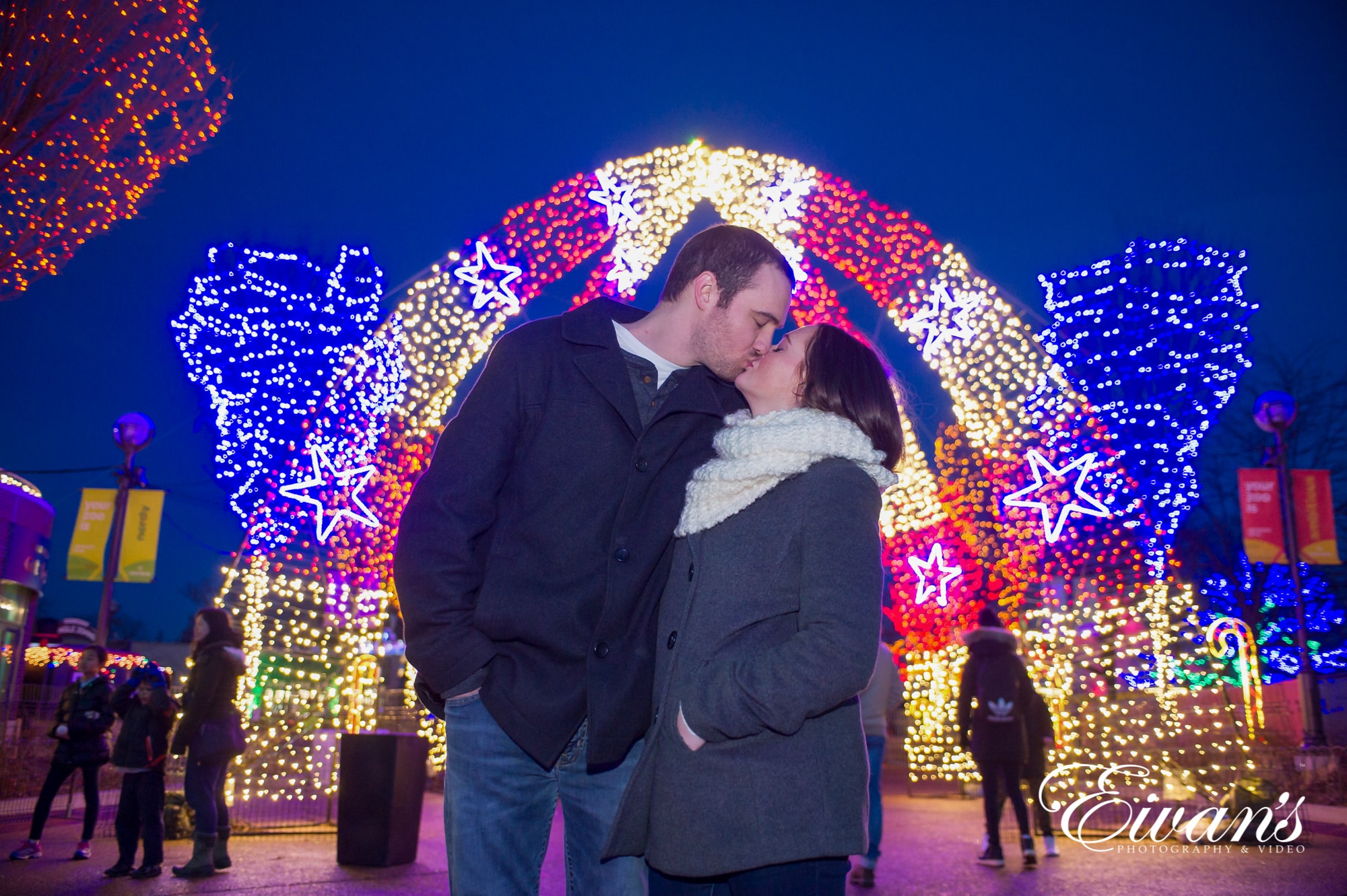 Image of a couple kissing in front of am arch of lights