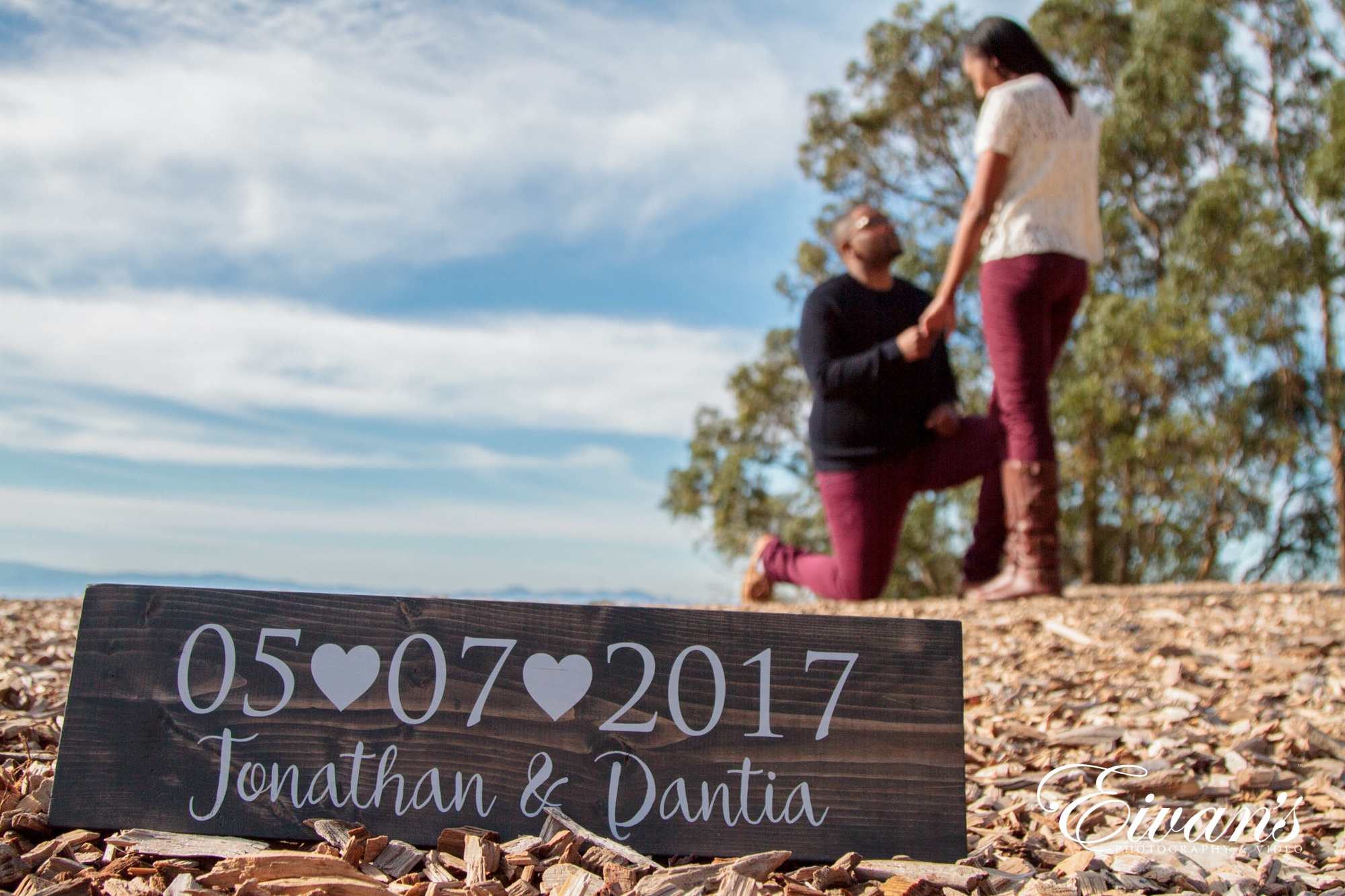 Image of a sign with a couples wedding date while the couple in the background