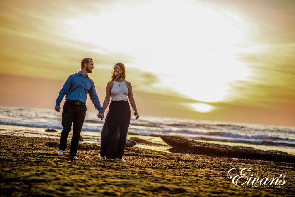 Image of a couple walking on the beach during sunset