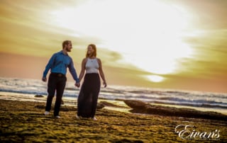 Image of a couple walking on the beach during sunset