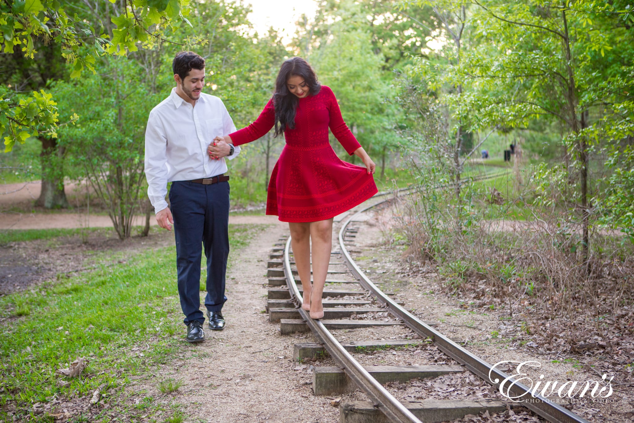 image of engaged couple walking along train tracks