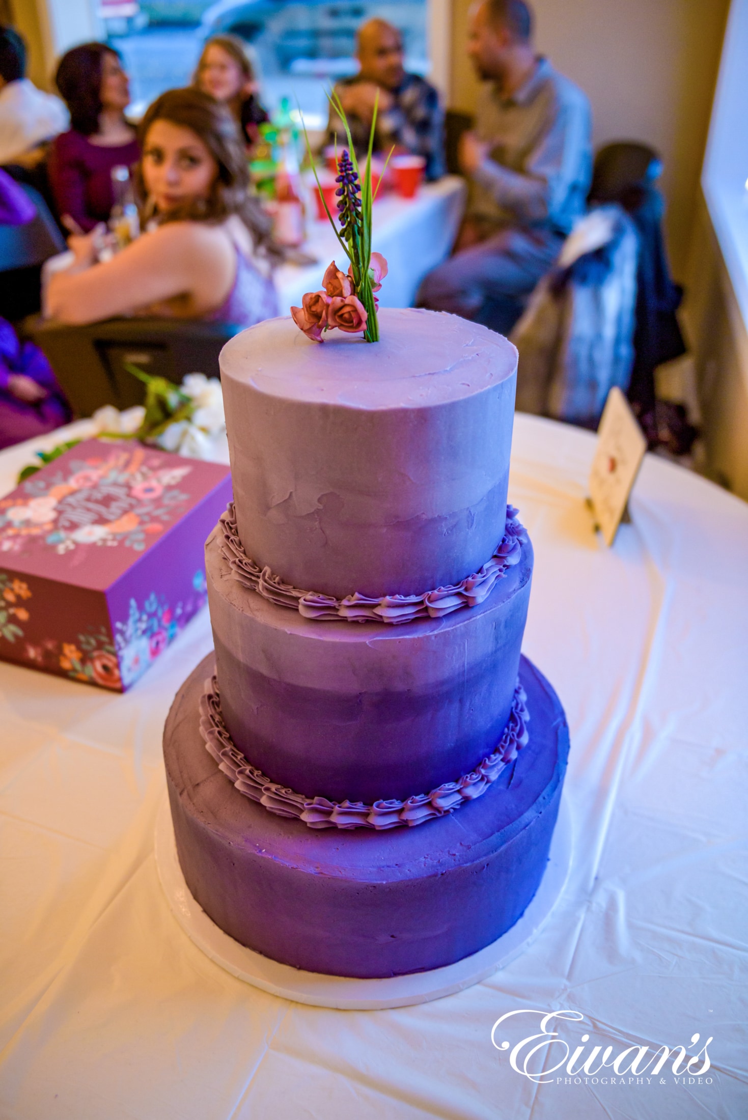 image of a three teared cake with purple frosting on it