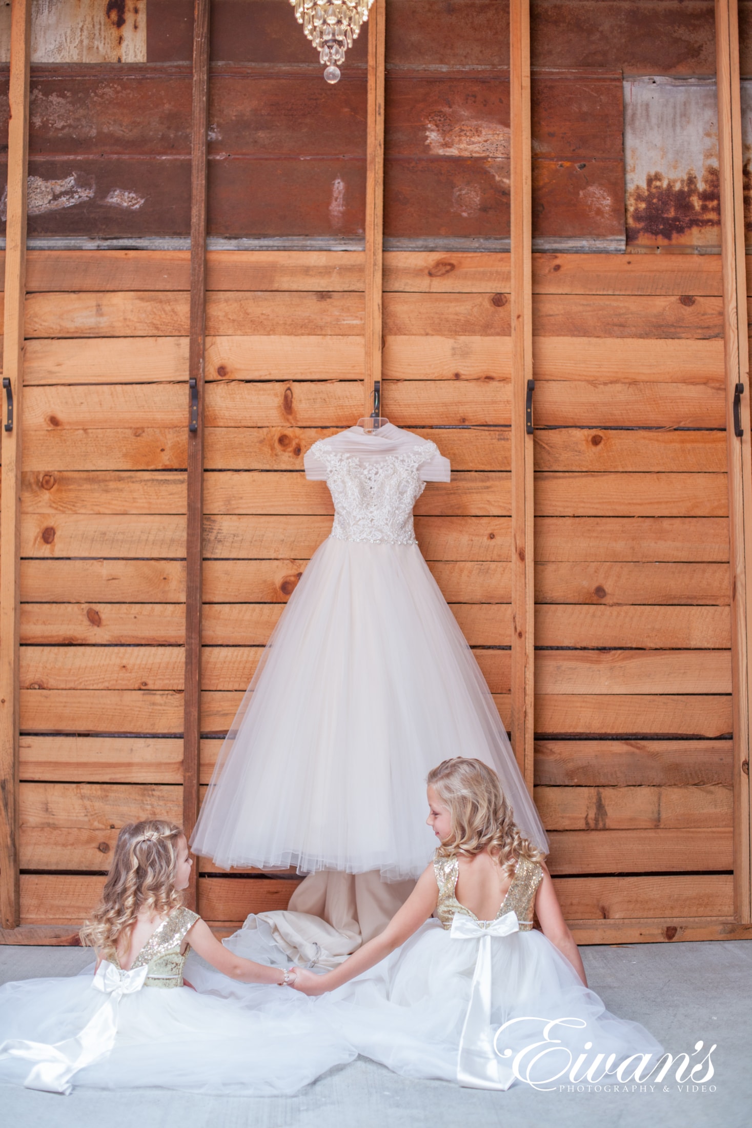 wedding-photography-shot-list image of two young girls sitting on the floor in front of a wedding dress