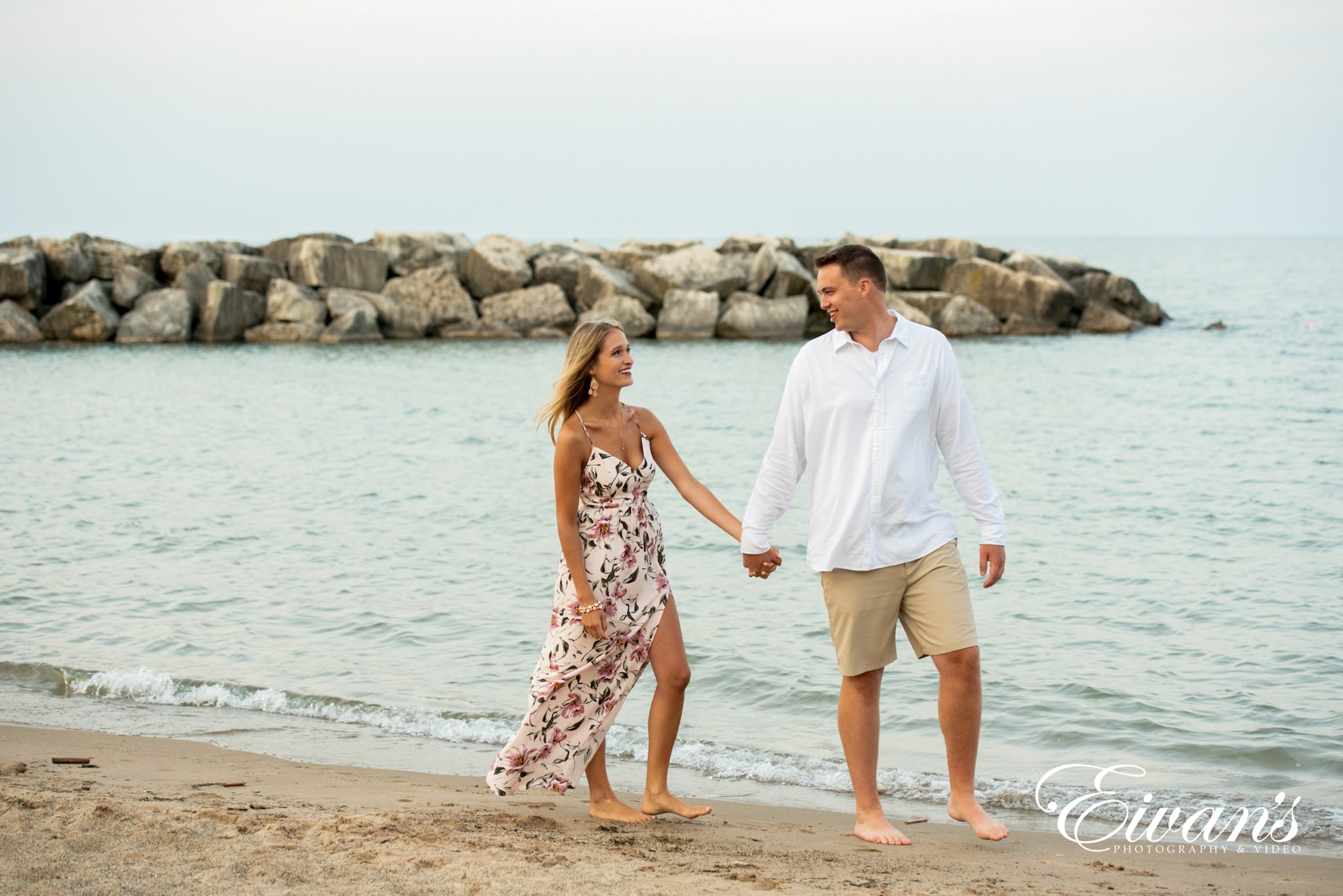 what-to-wear-for-summer-engagement-photos image of engaged couple walking on the beach