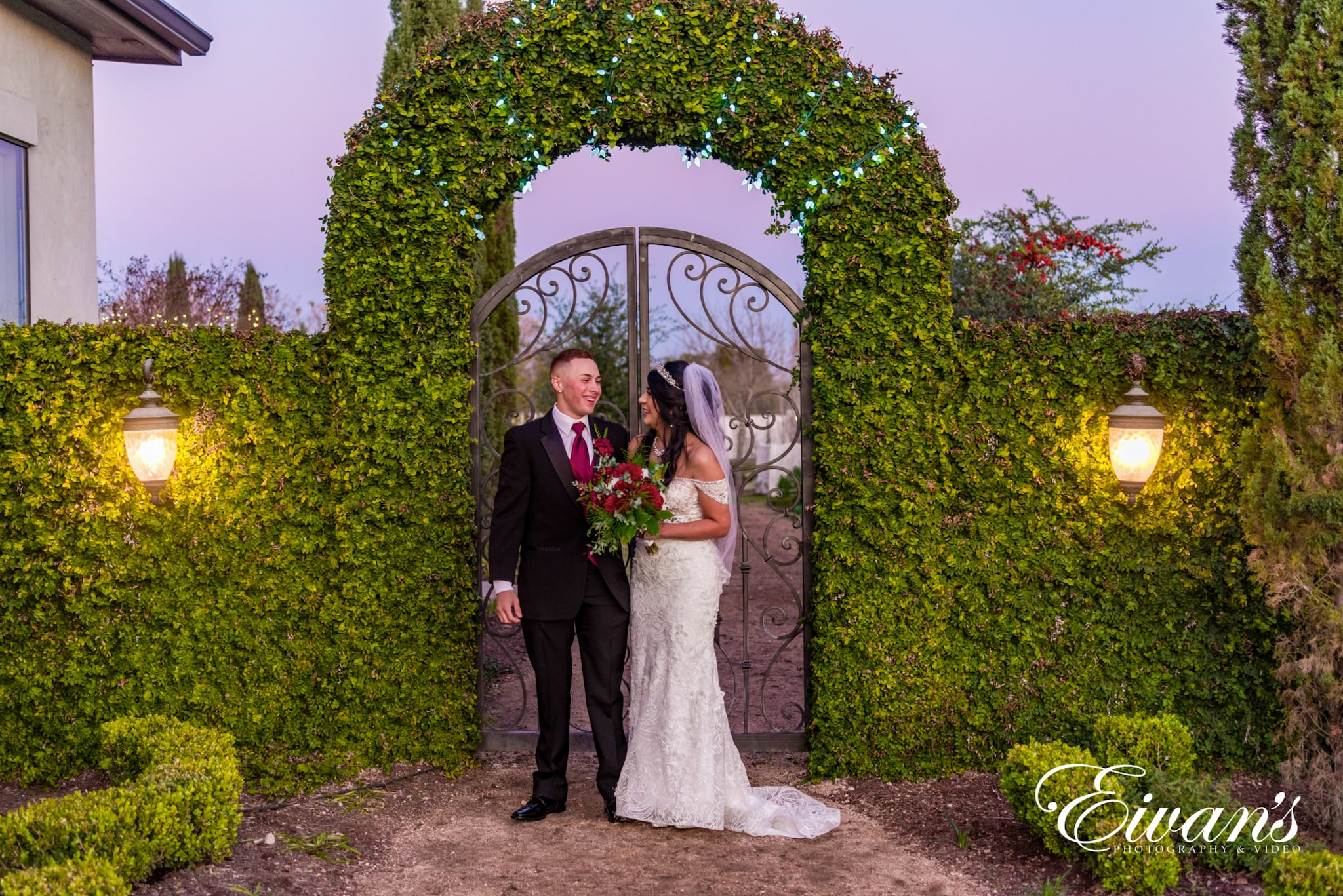 image of a married couple in front of a greenery archway