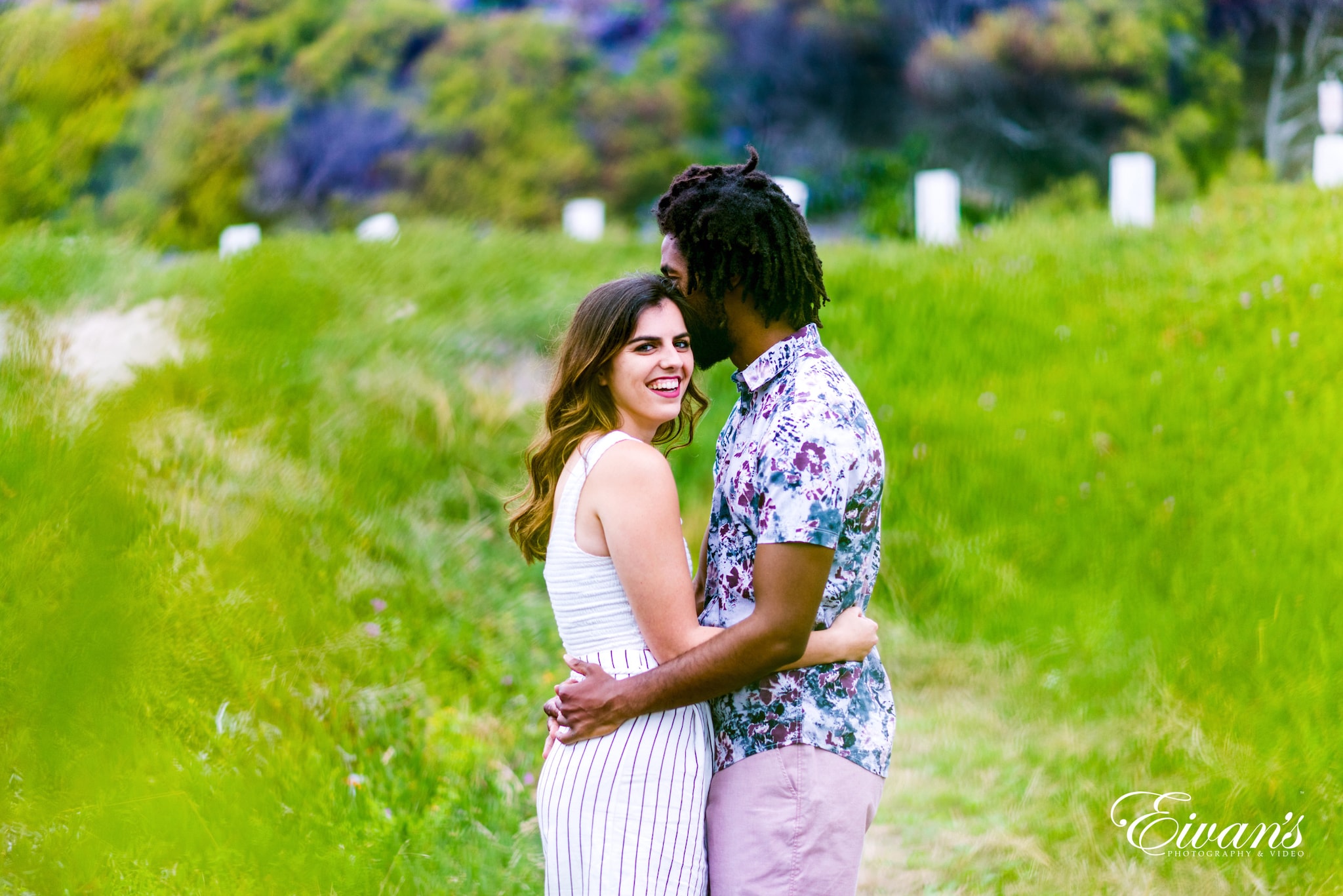 woman in white and black floral dress hugging man in white and black stripe shirt