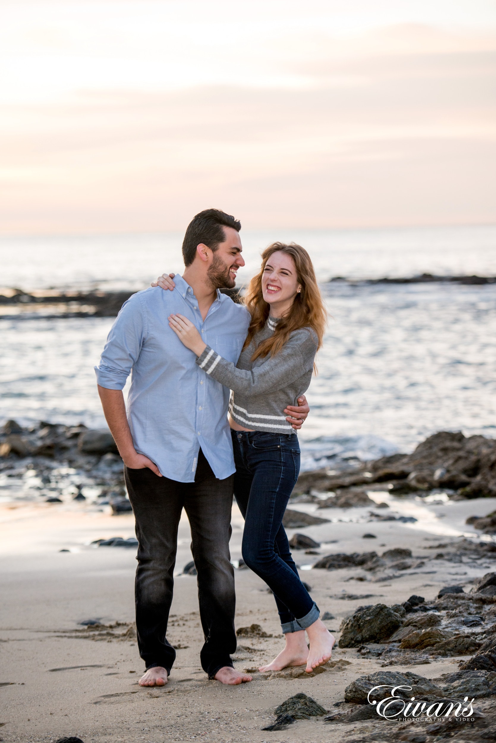 man in white dress shirt kissing woman in gray long sleeve shirt on beach during daytime