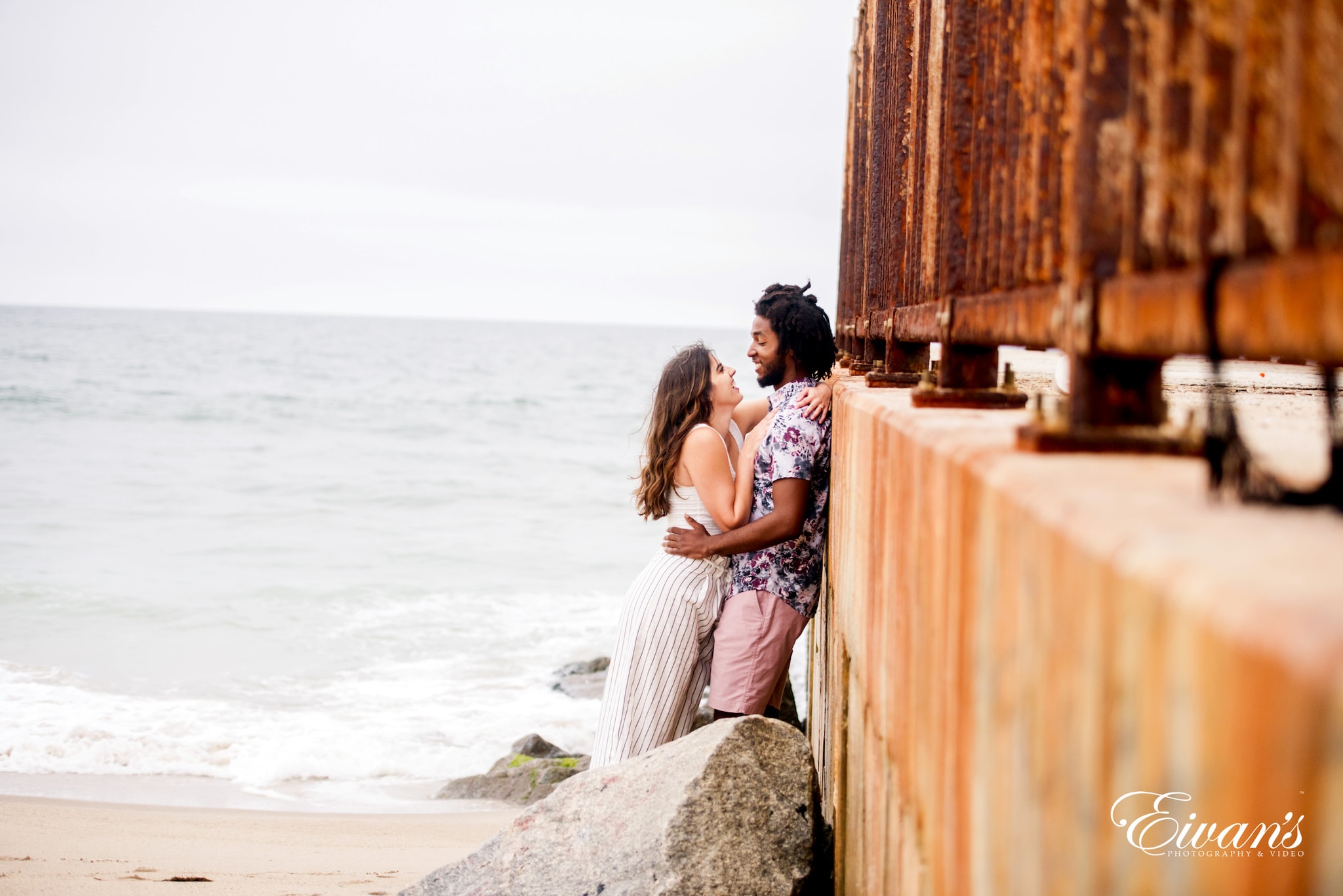 couple sitting on concrete wall near sea during daytime