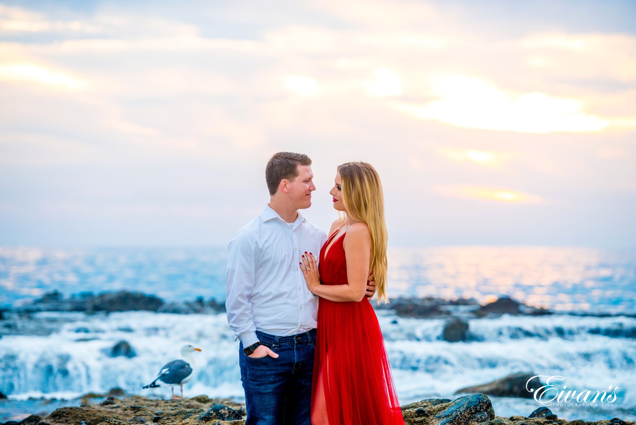 man in white dress shirt and woman in orange dress standing on rocky shore during daytime