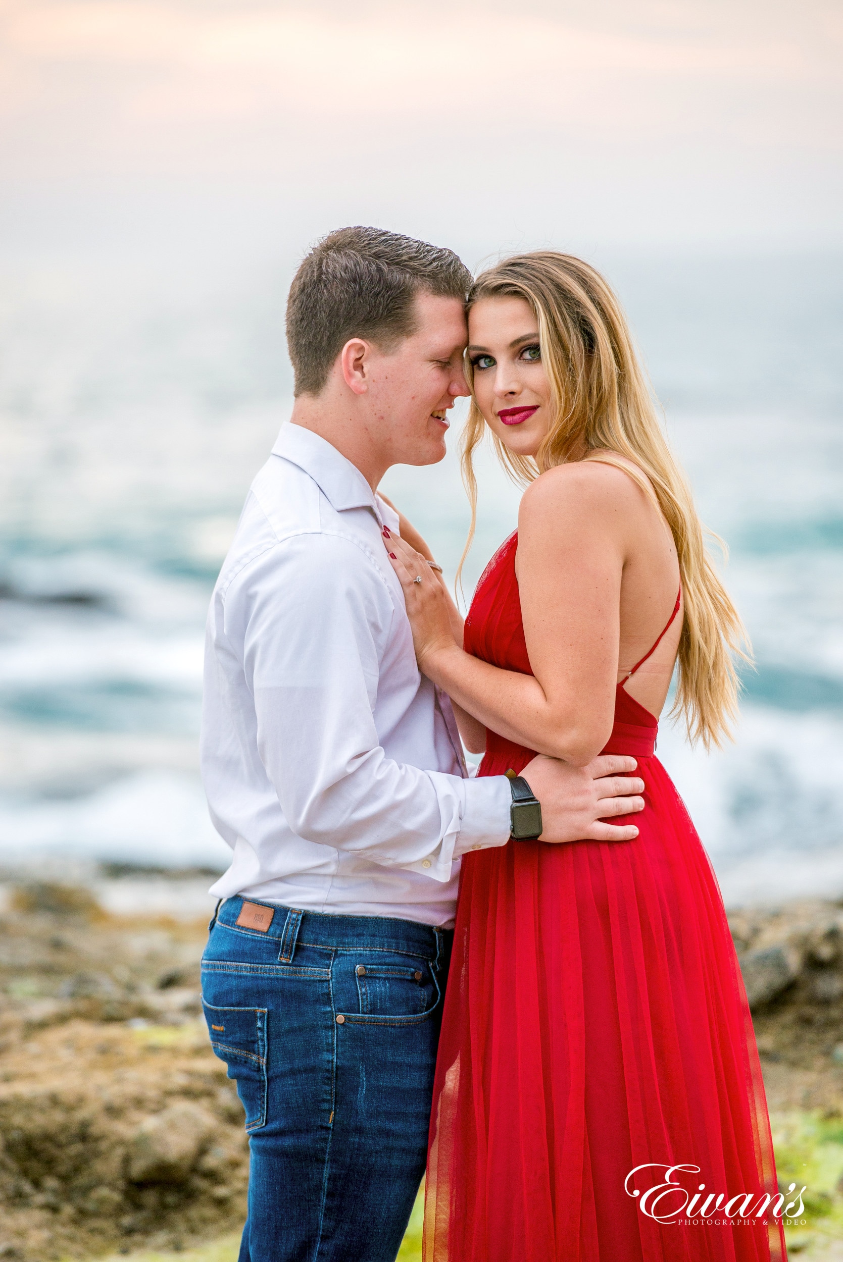 man in white dress shirt kissing woman in red dress on seashore during daytime