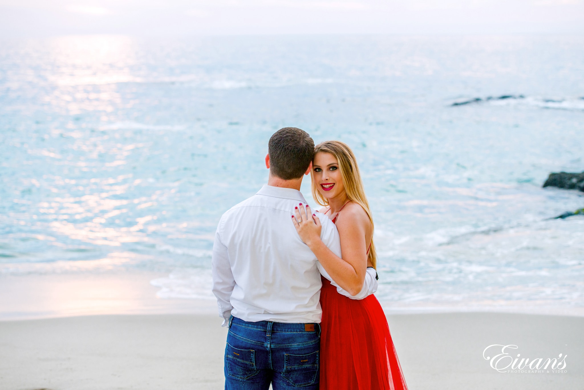 man in white dress shirt kissing woman in red dress on beach during daytime