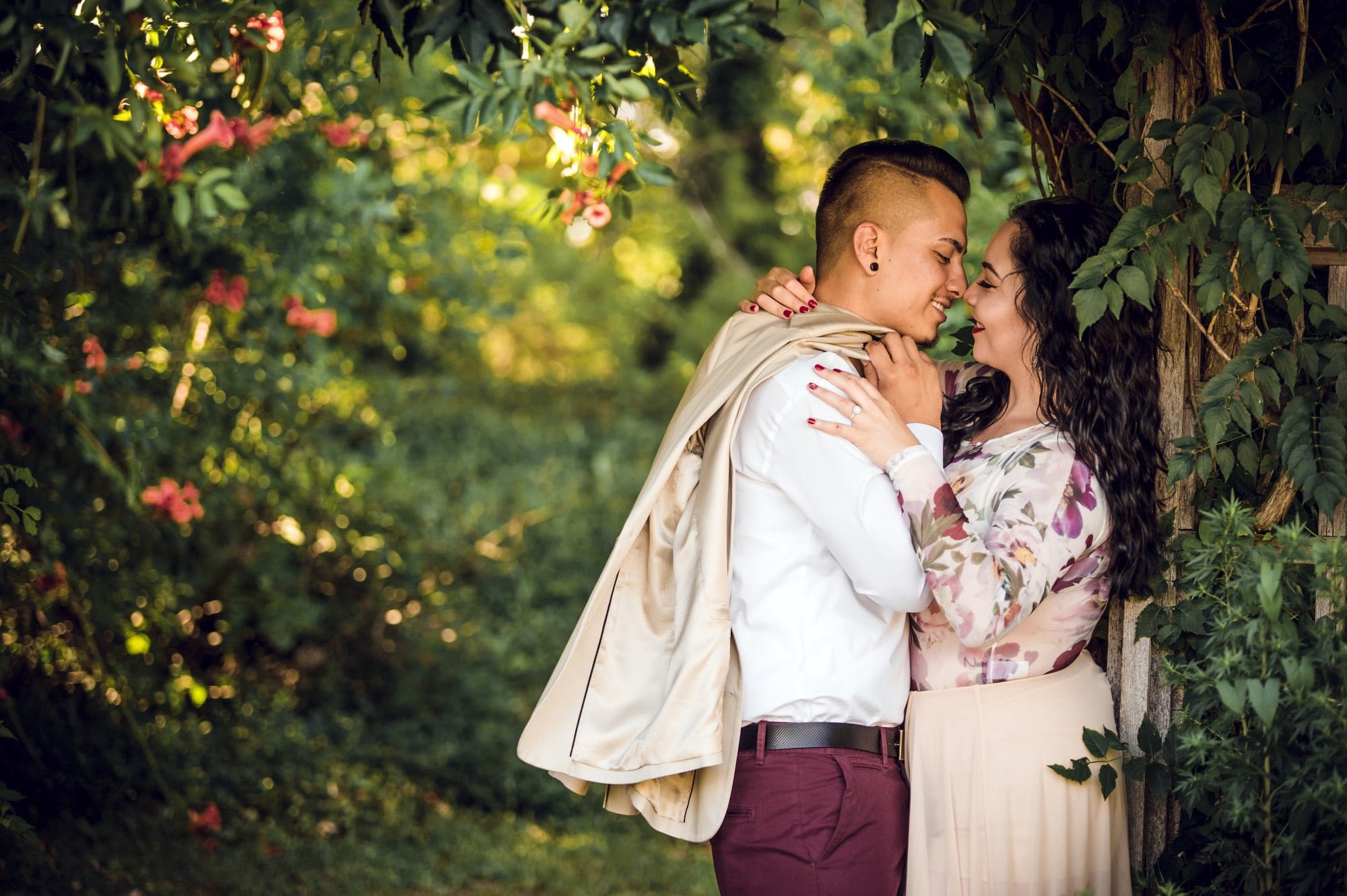 man and woman kissing near trees