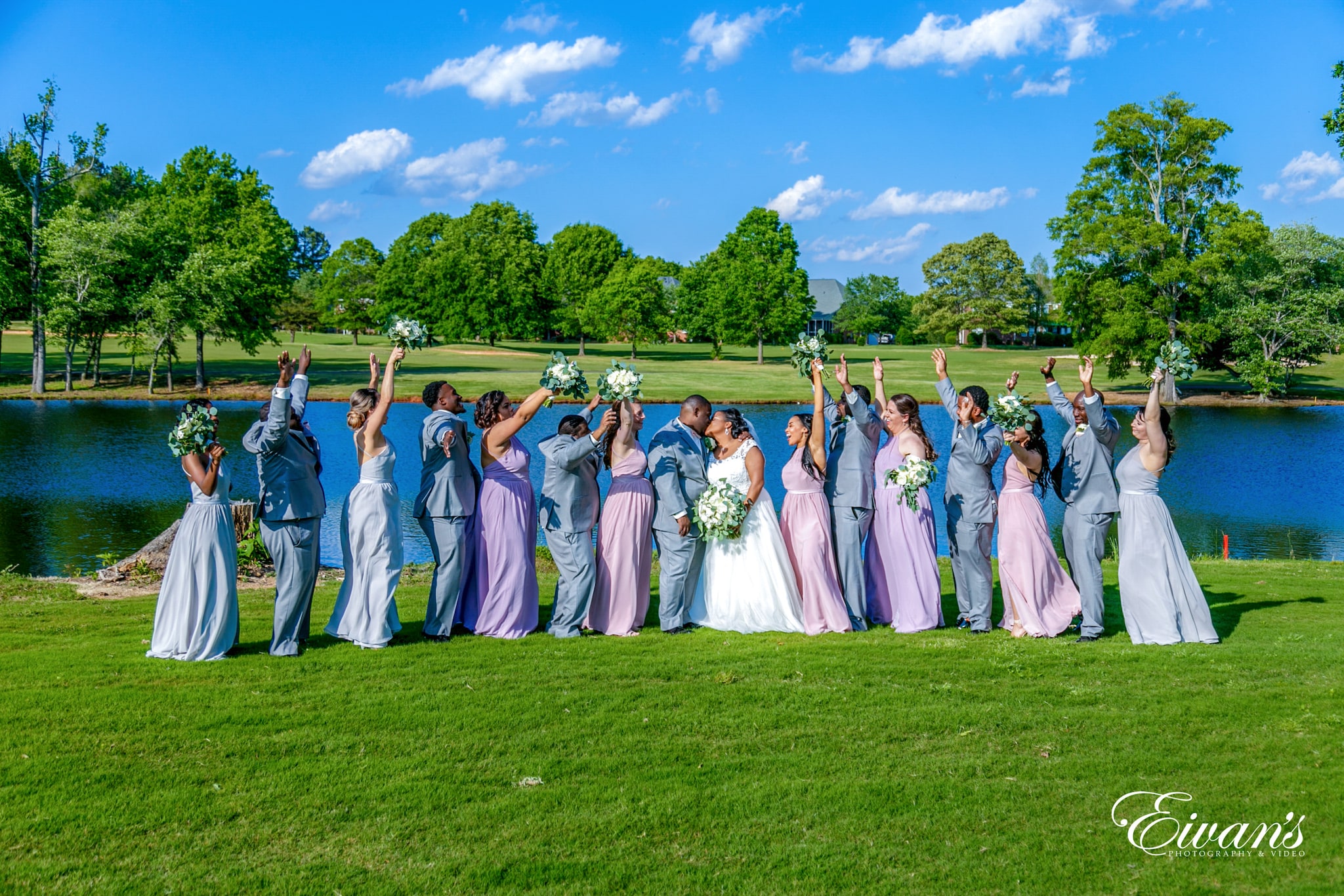 The wedding attire of groomsmen, bridesmaids, and guests wedding party standing on green grass field during daytime