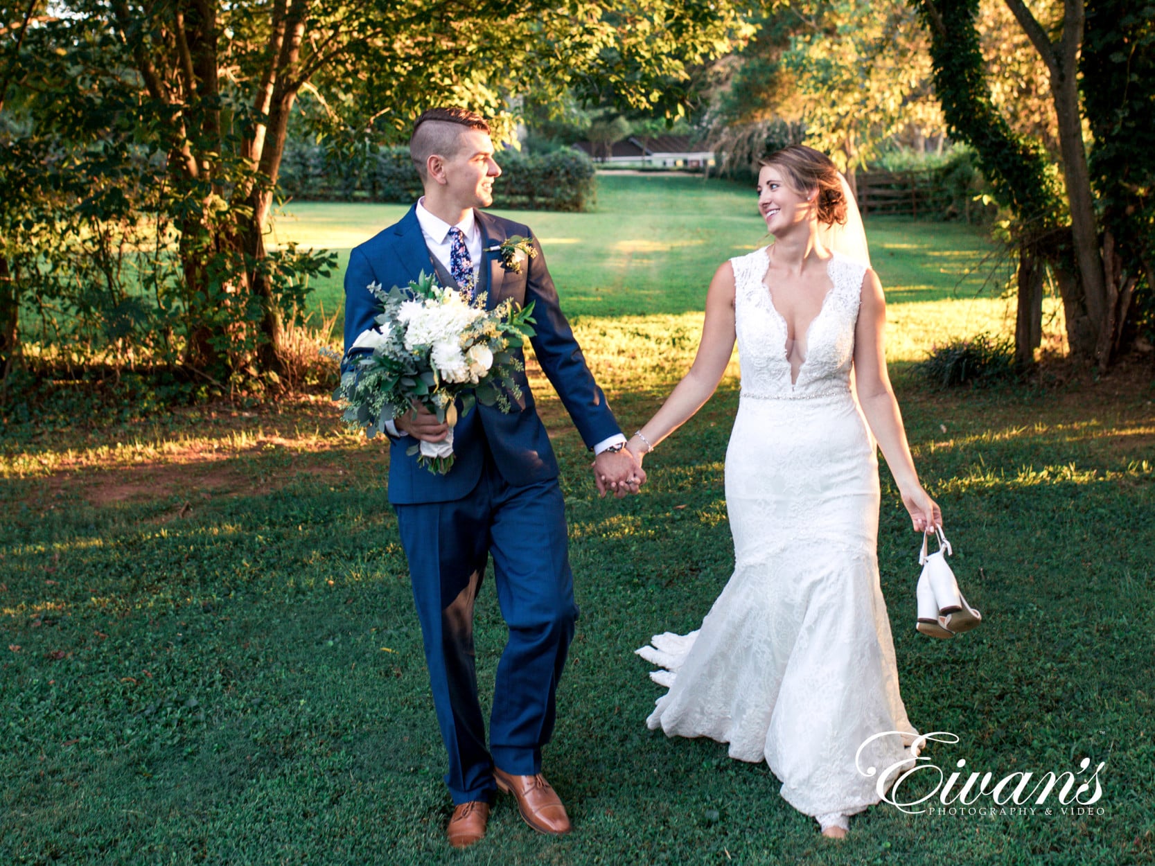 man in black suit and woman in white wedding dress holding bouquet of flowers