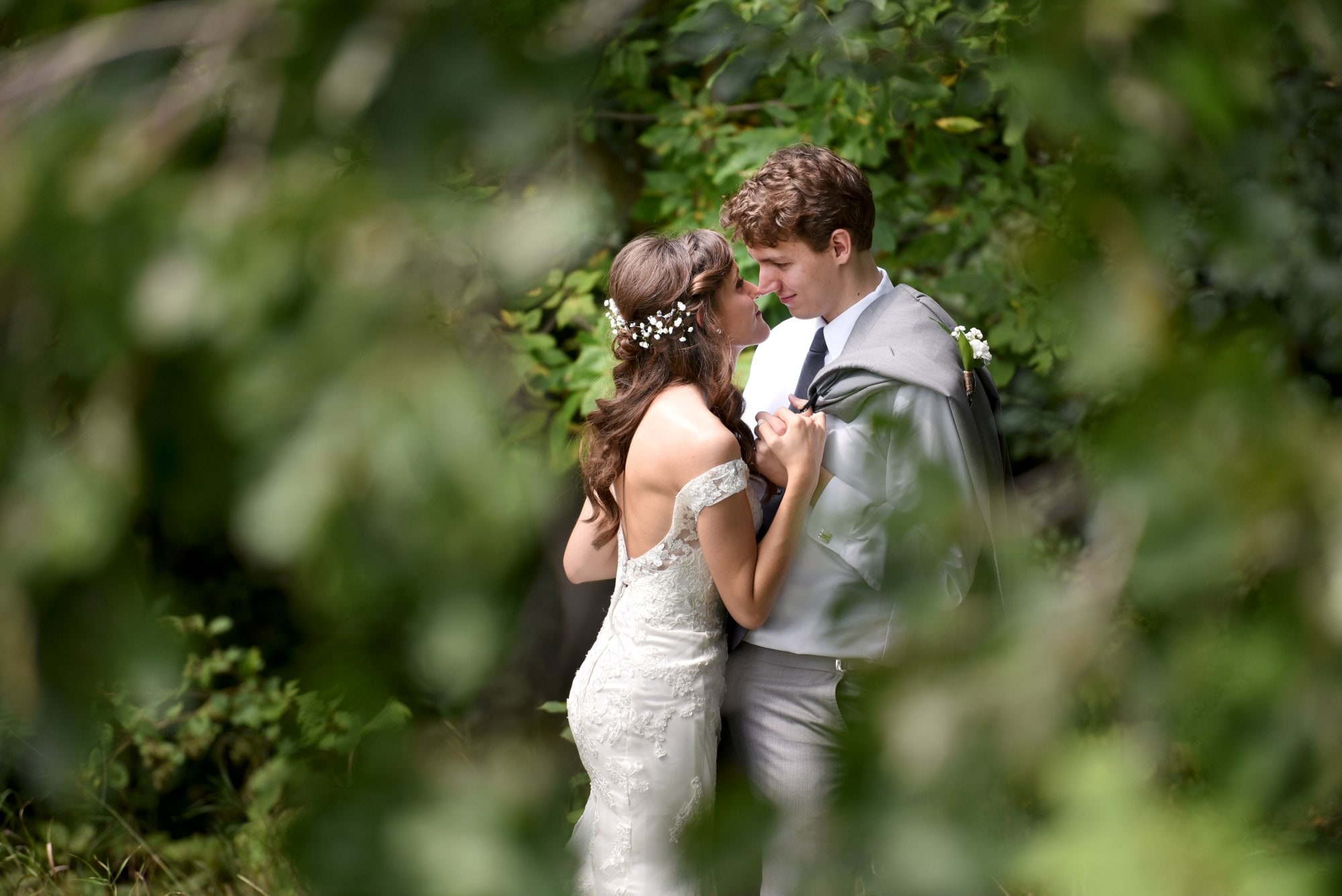 man in gray suit kissing woman in white wedding dress