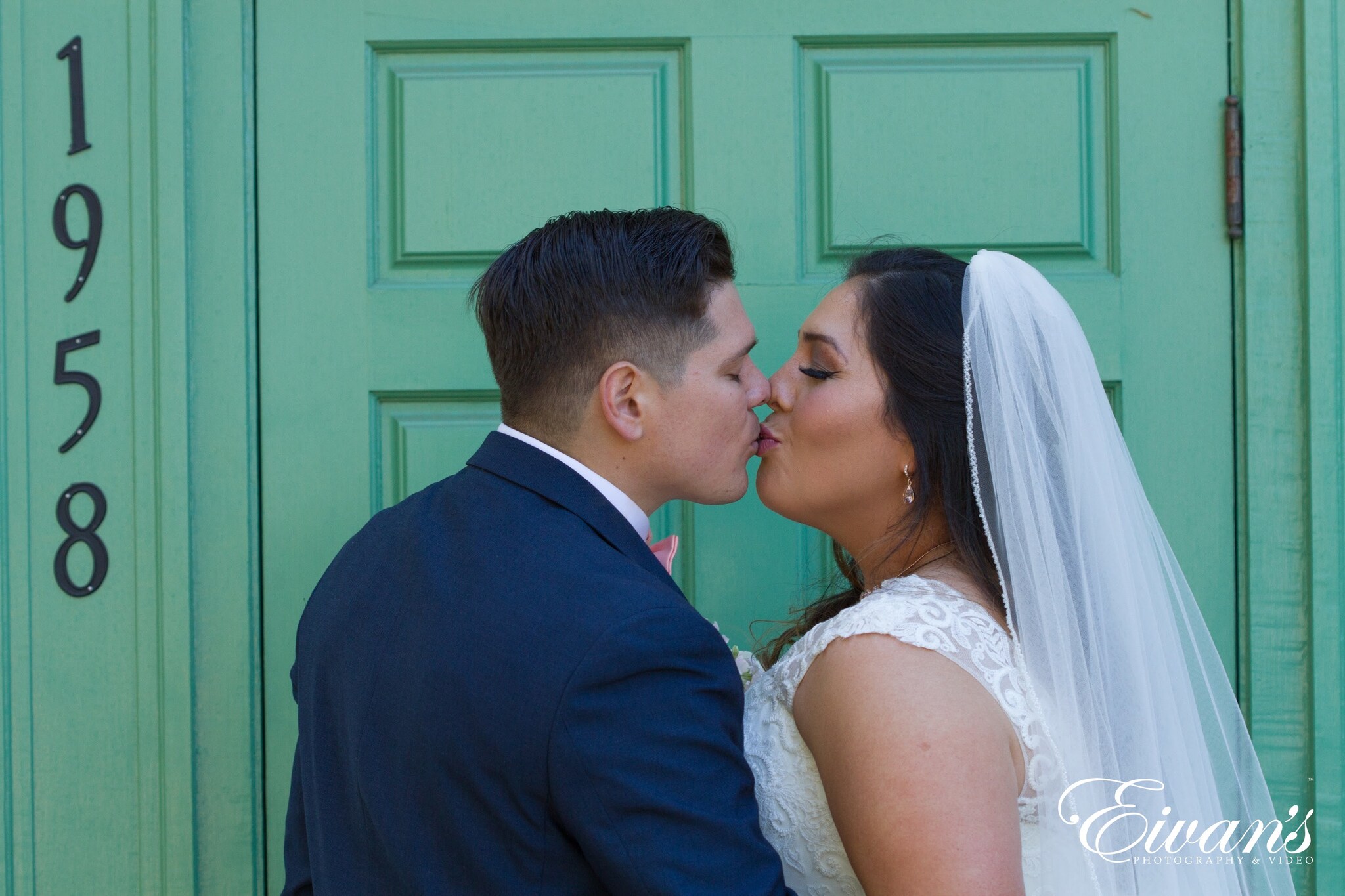 man in black suit kissing woman in white wedding dress