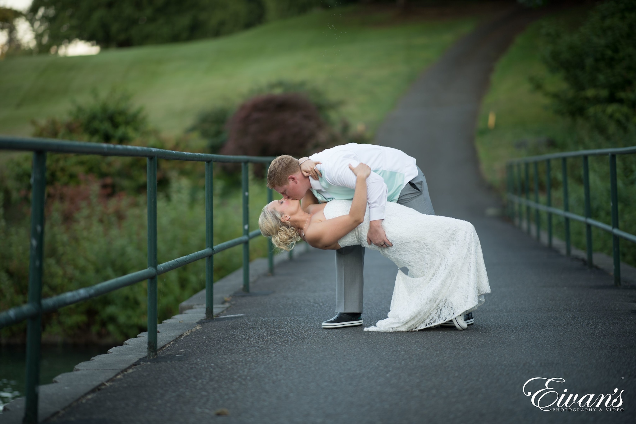 man in white t-shirt carrying baby in white dress on gray concrete road during daytime