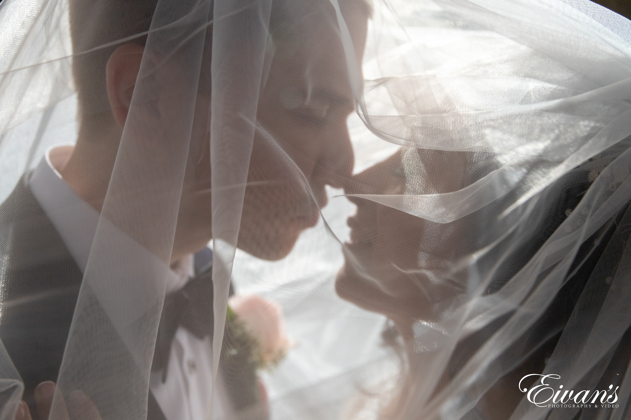 man and woman kissing under a white mesh net
