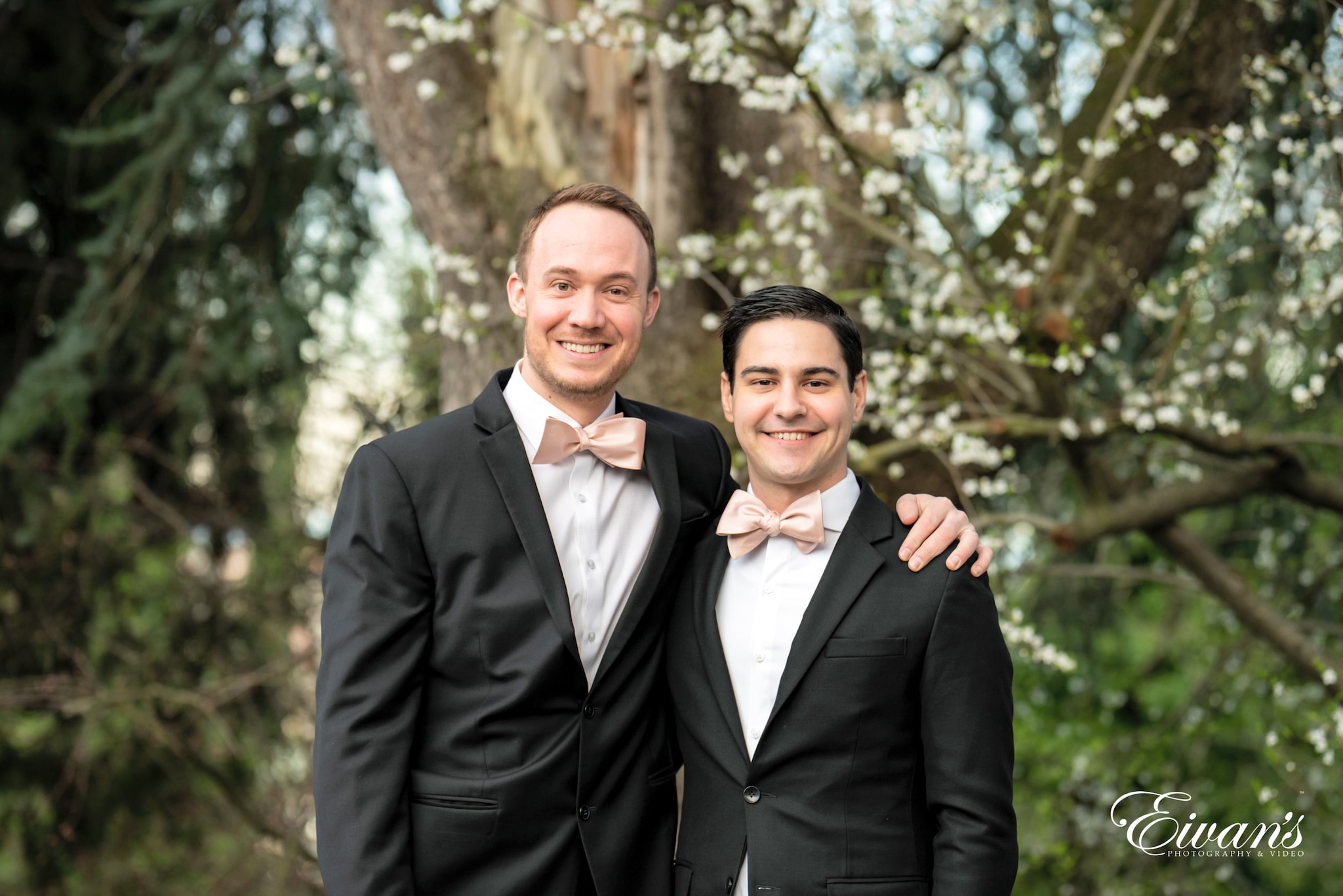 man in black suit jacket smiling beside man in black suit