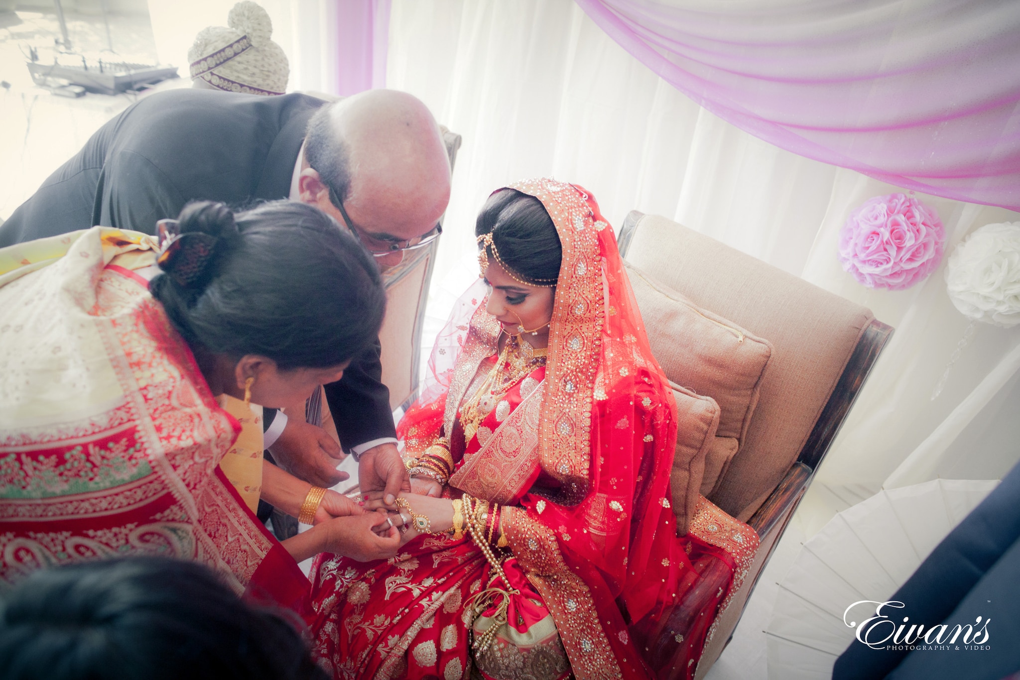 woman in red and gold sari sitting on brown couch