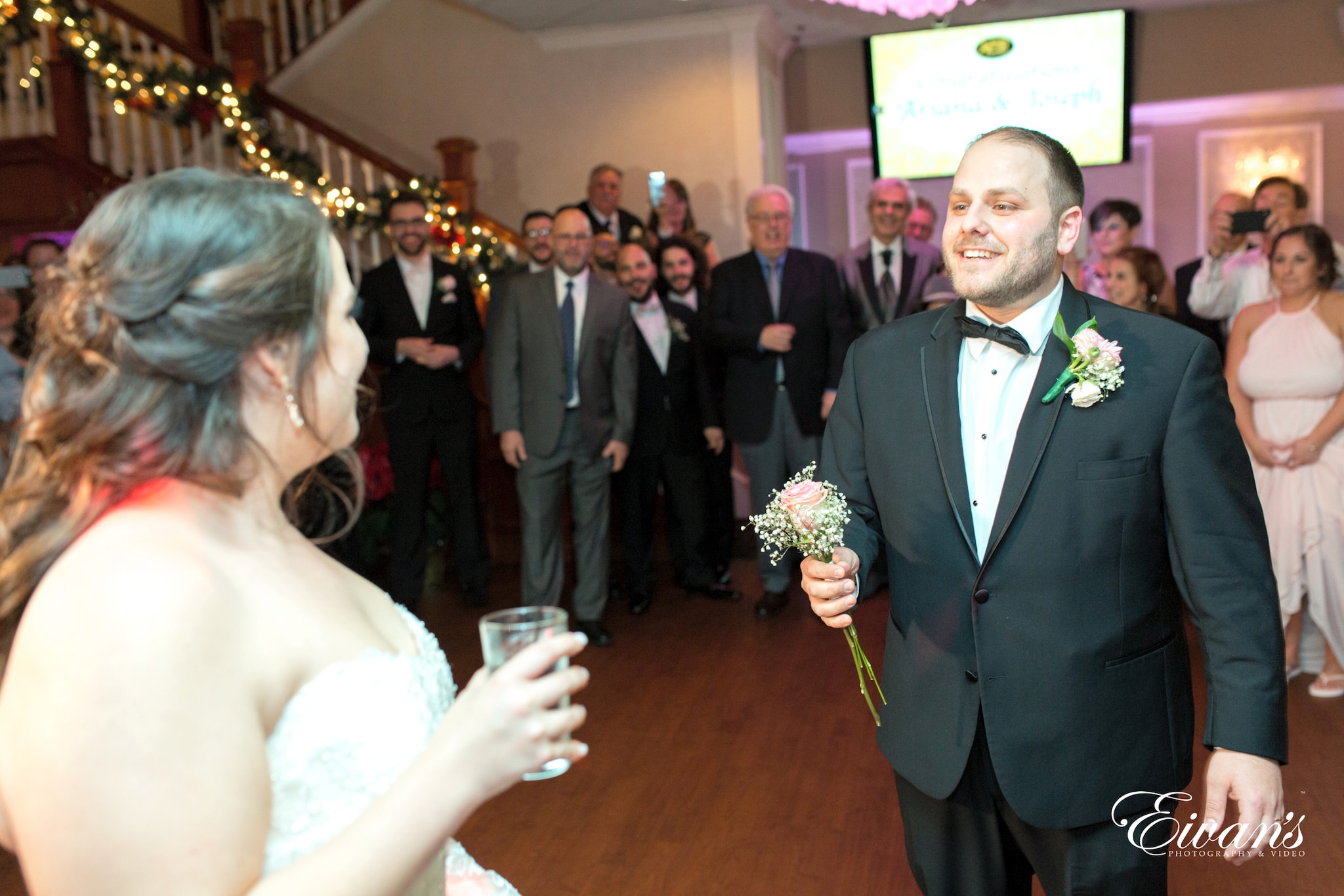man in black suit jacket holding woman in white wedding dress