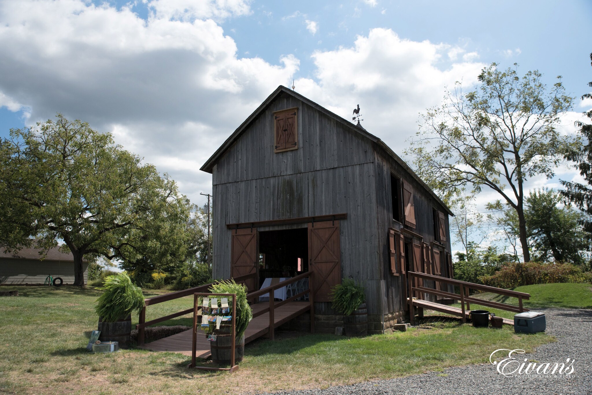 brown wooden house near green trees under white clouds during daytime