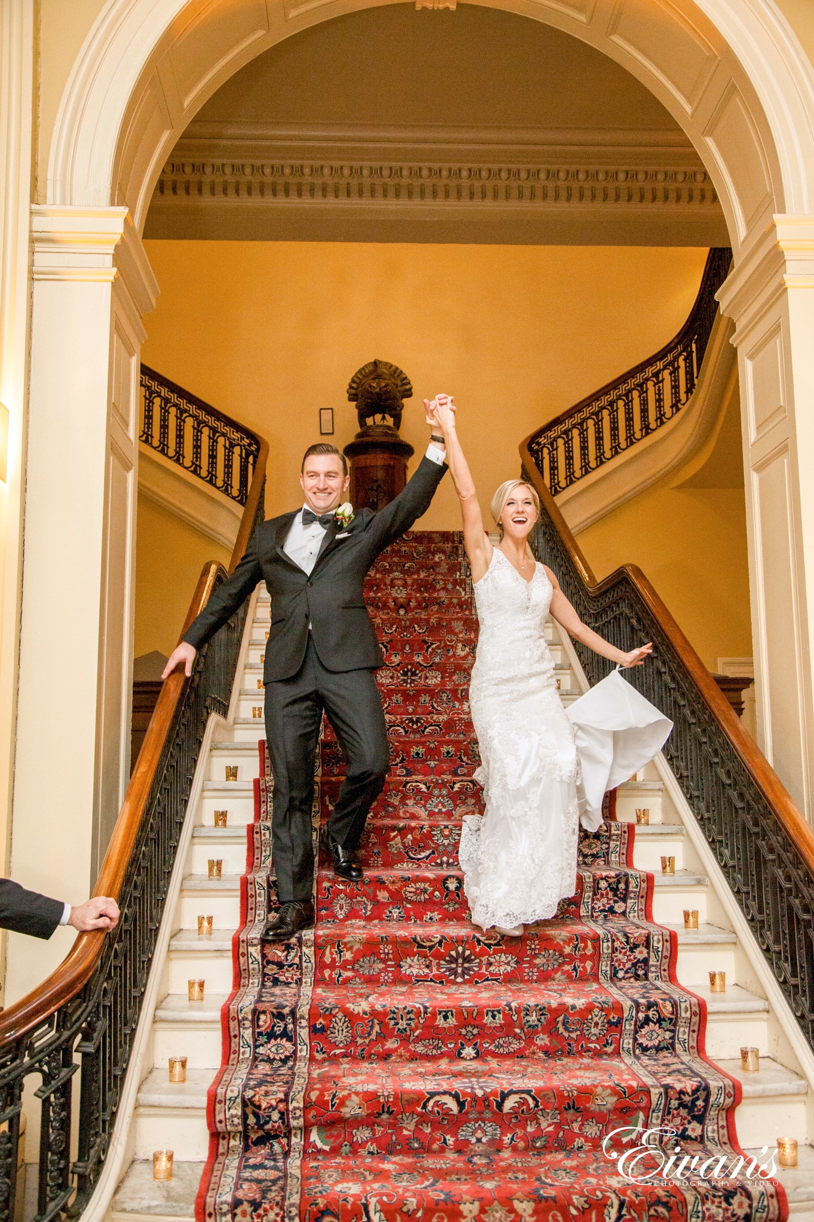 man in black suit kissing woman in white wedding dress on brown staircase