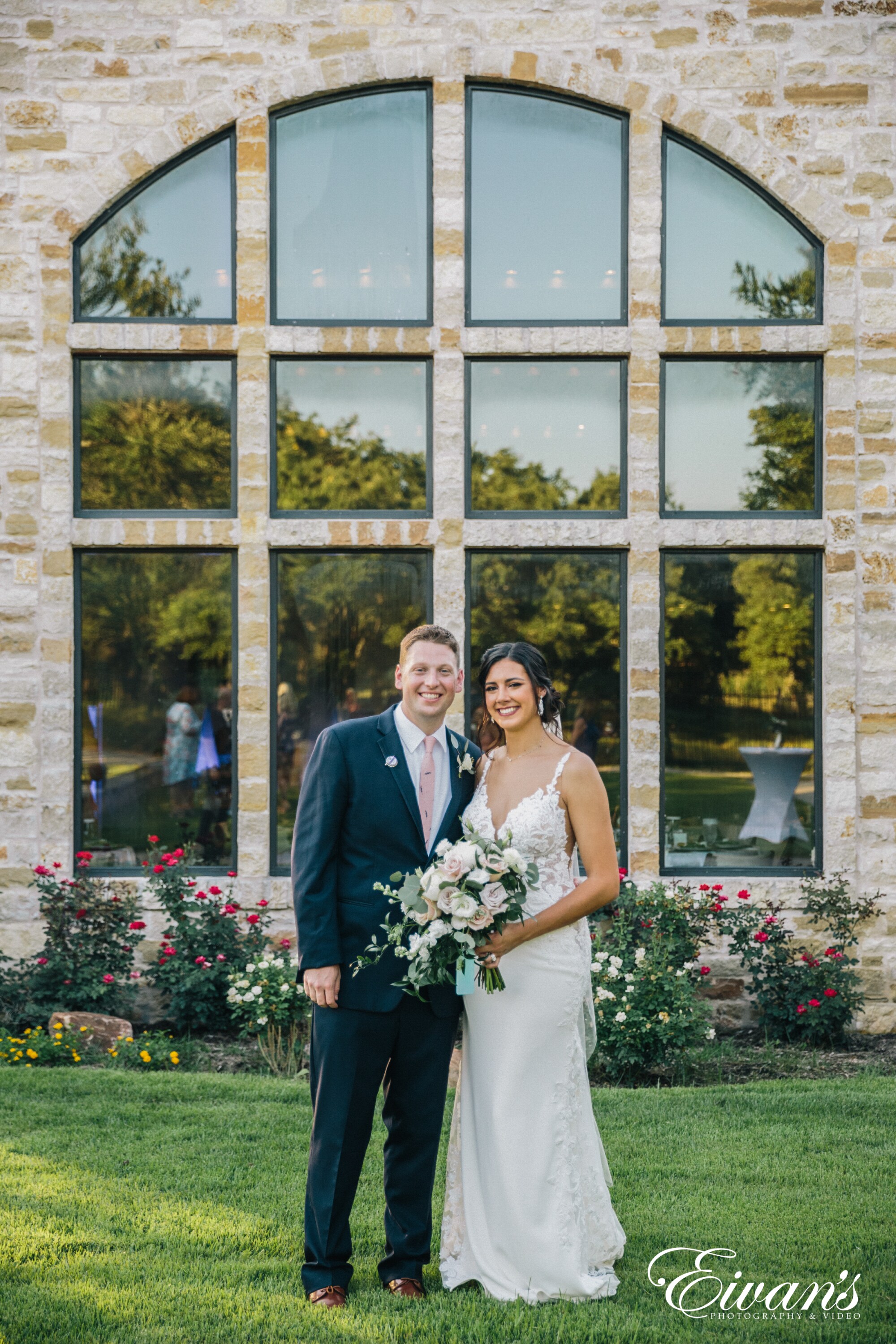 man in black suit and woman in white wedding dress holding bouquet of flowers