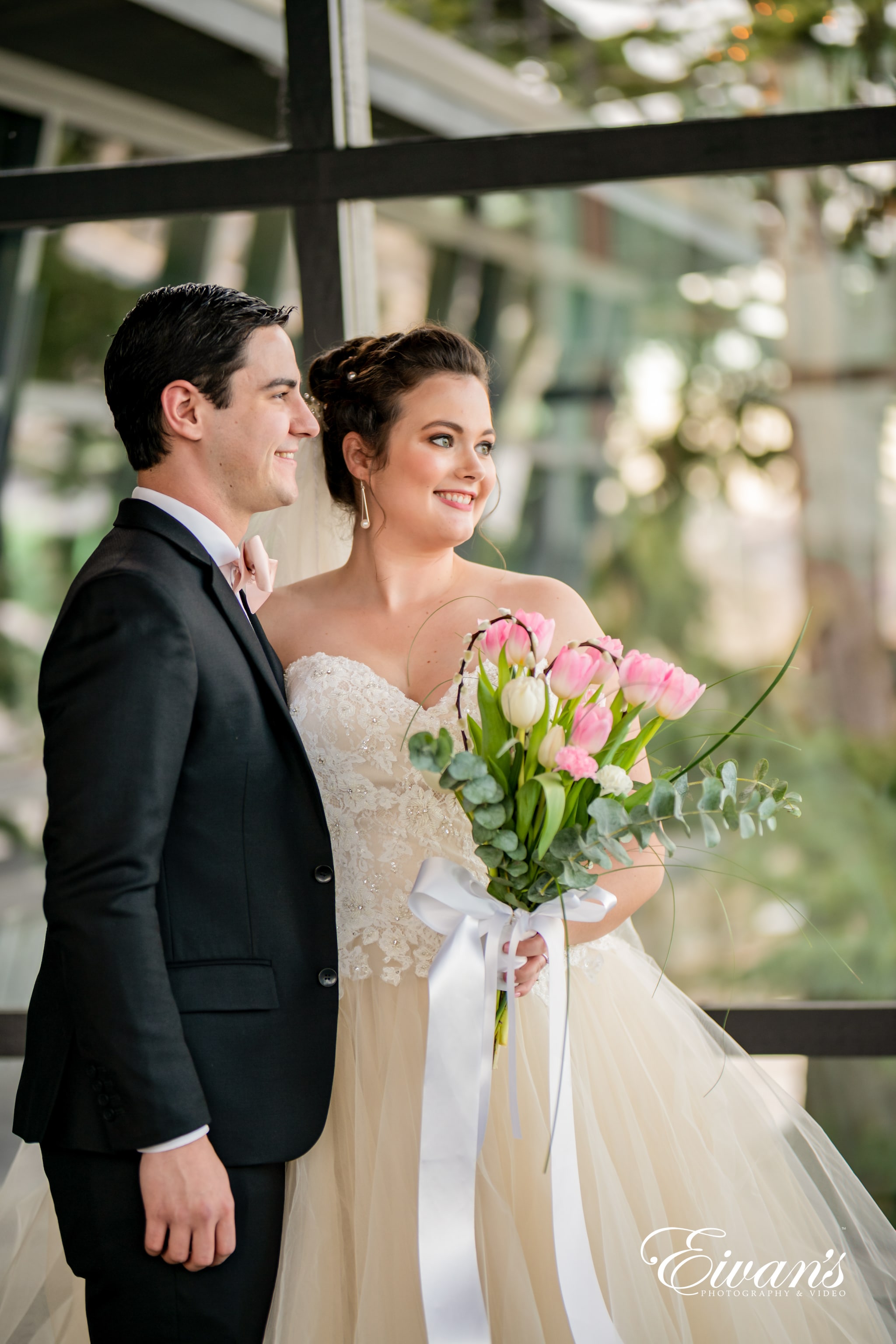 man in black suit and woman in white wedding dress holding bouquet of flowers