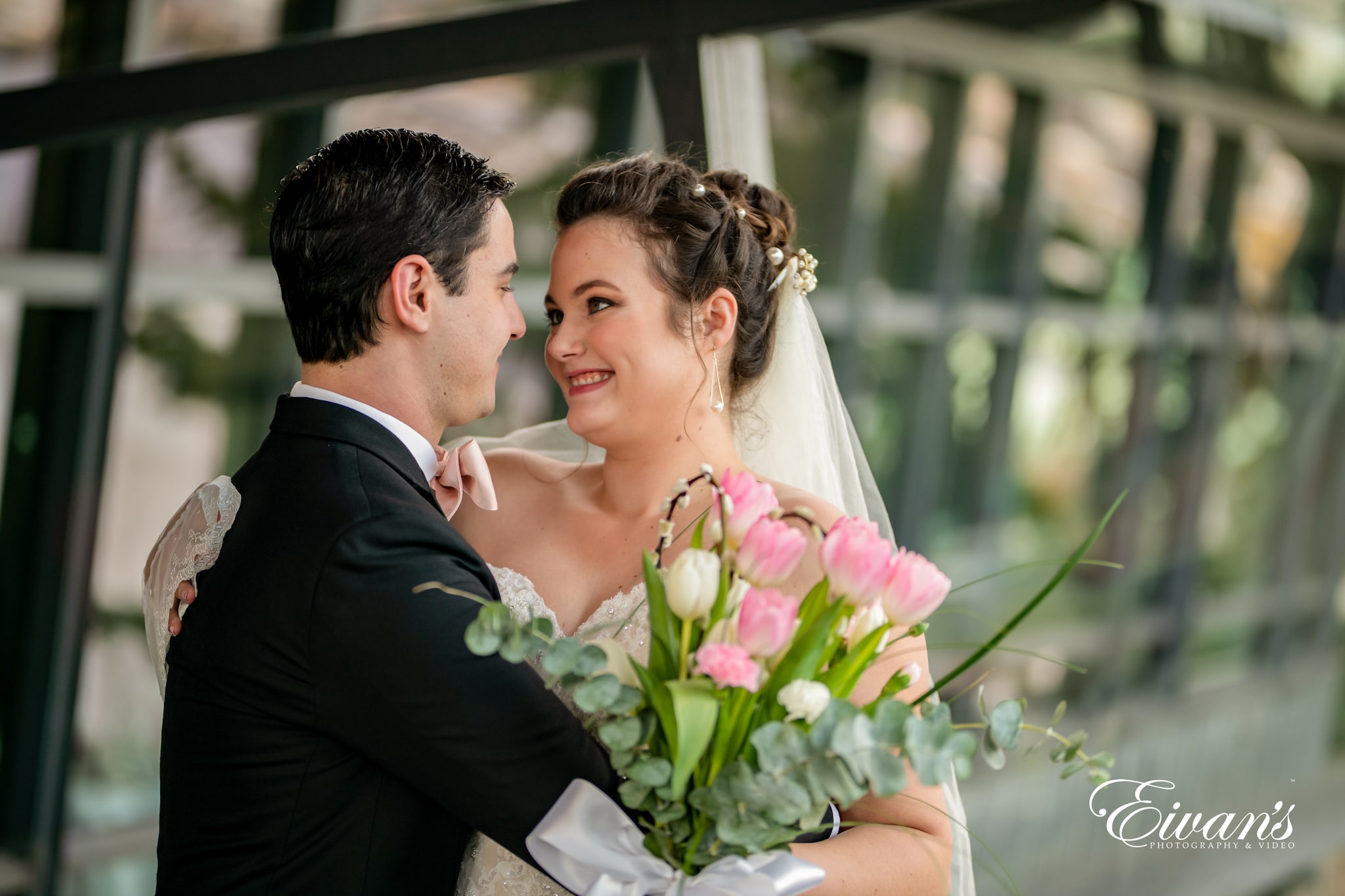 man in black suit kissing woman in pink and white floral wedding dress