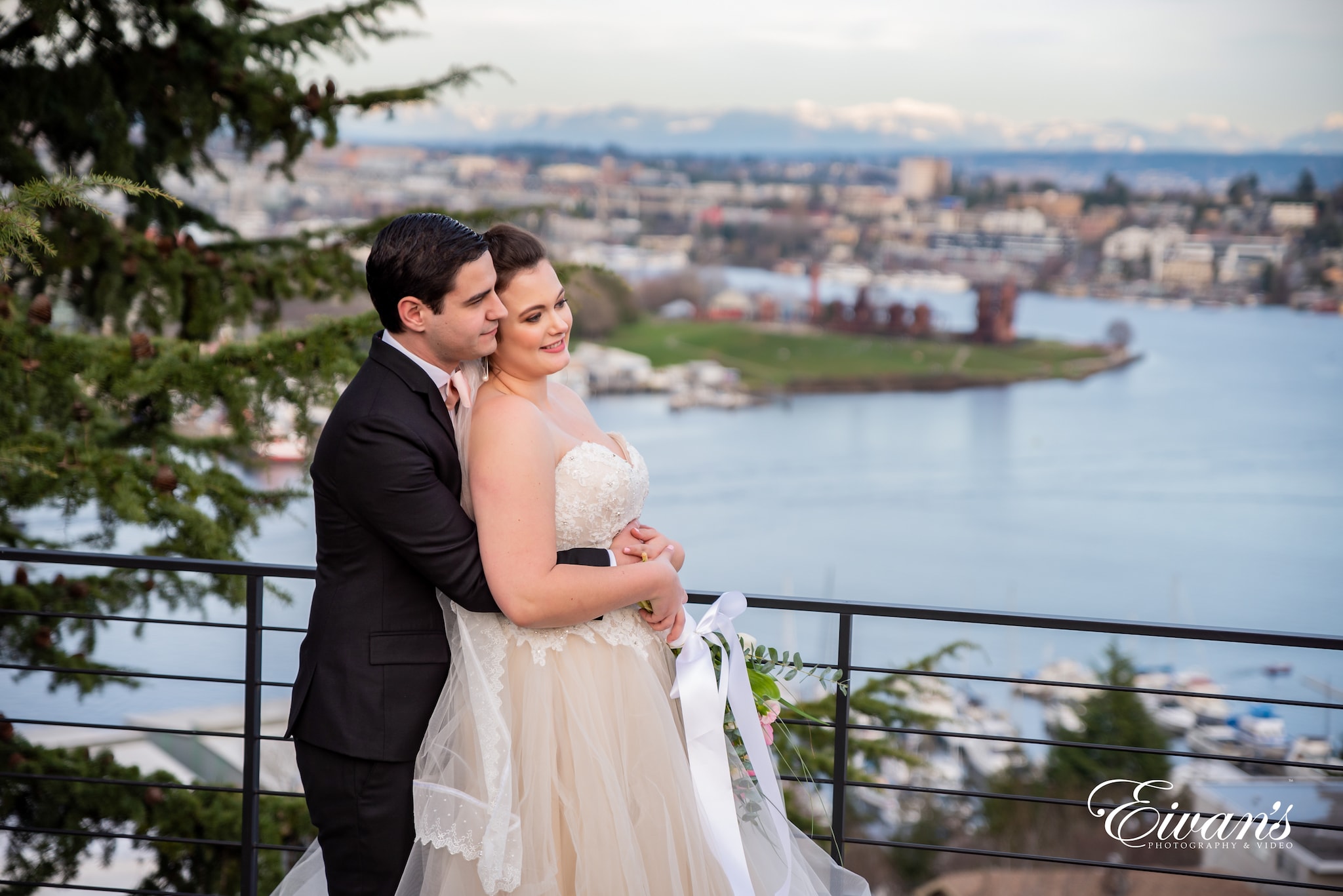 man in black suit kissing woman in white wedding dress on bridge during daytime