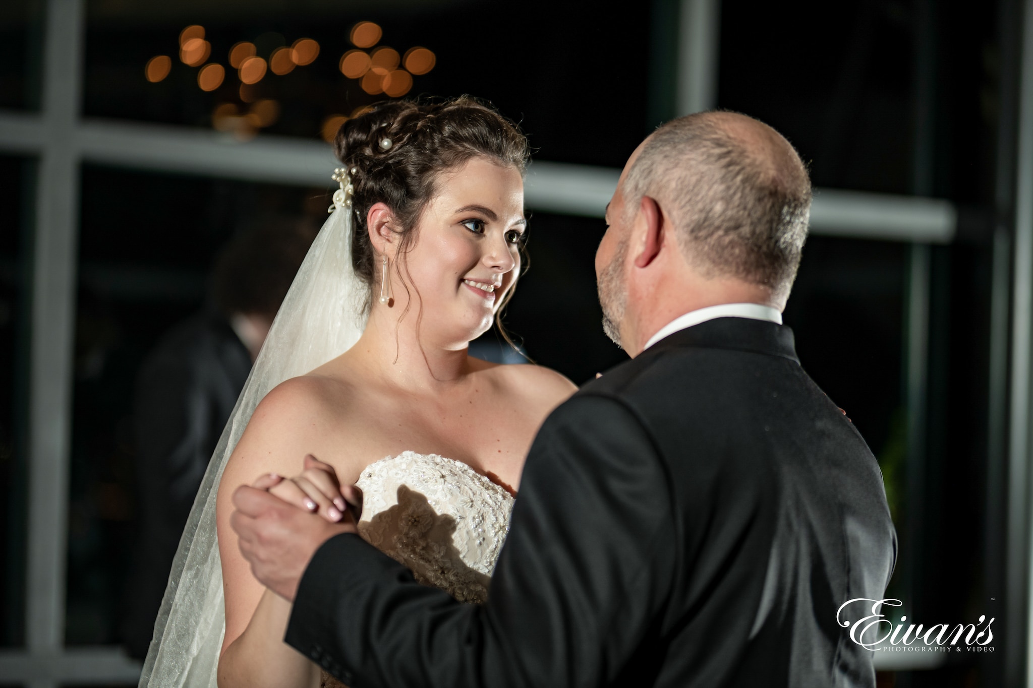 man in black suit kissing woman in white floral wedding dress