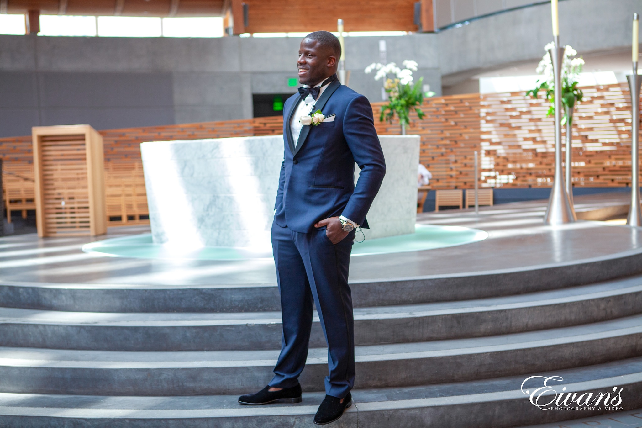 man in blue suit jacket and black pants standing on gray concrete staircase