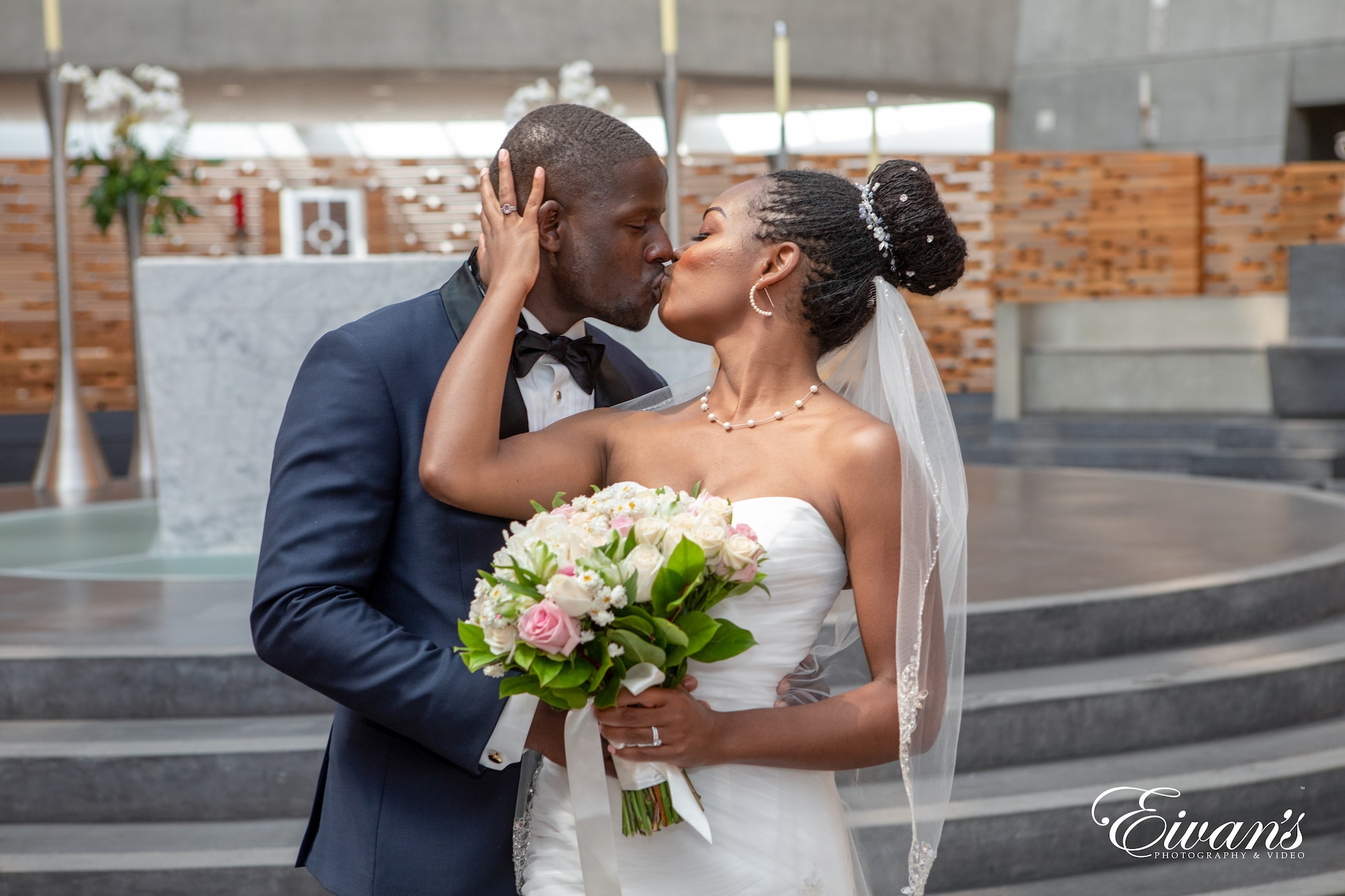 man in blue suit jacket kissing woman in white wedding dress