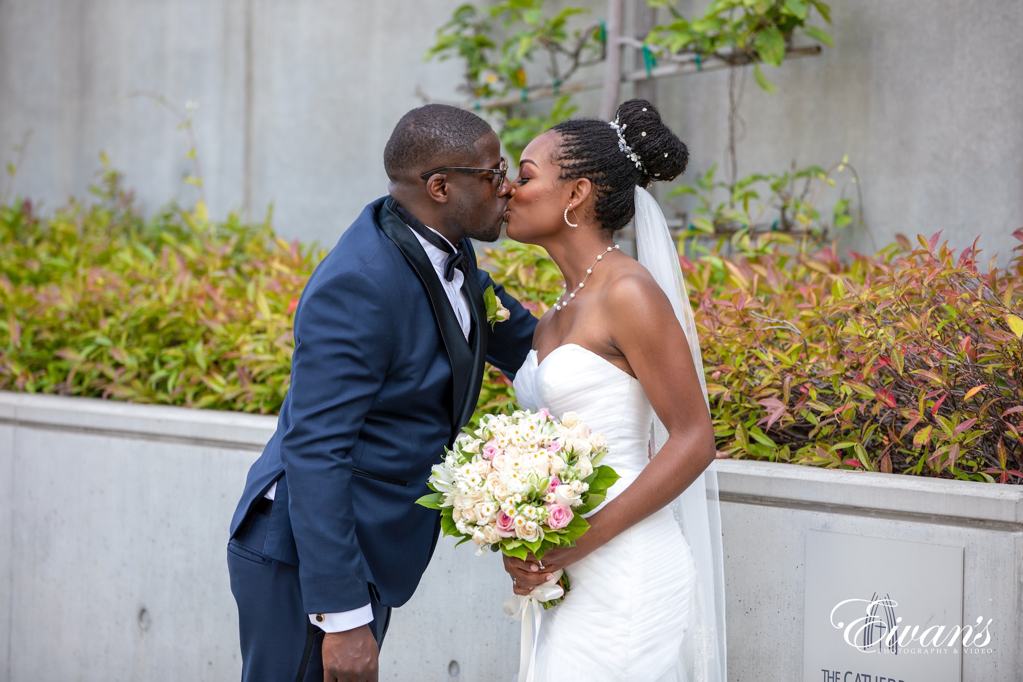 man in blue suit kissing woman in white wedding dress