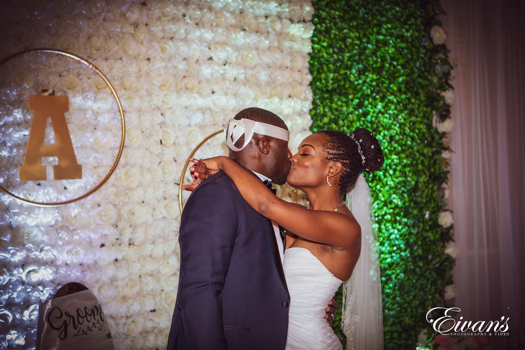man in black suit kissing woman in white sleeveless dress