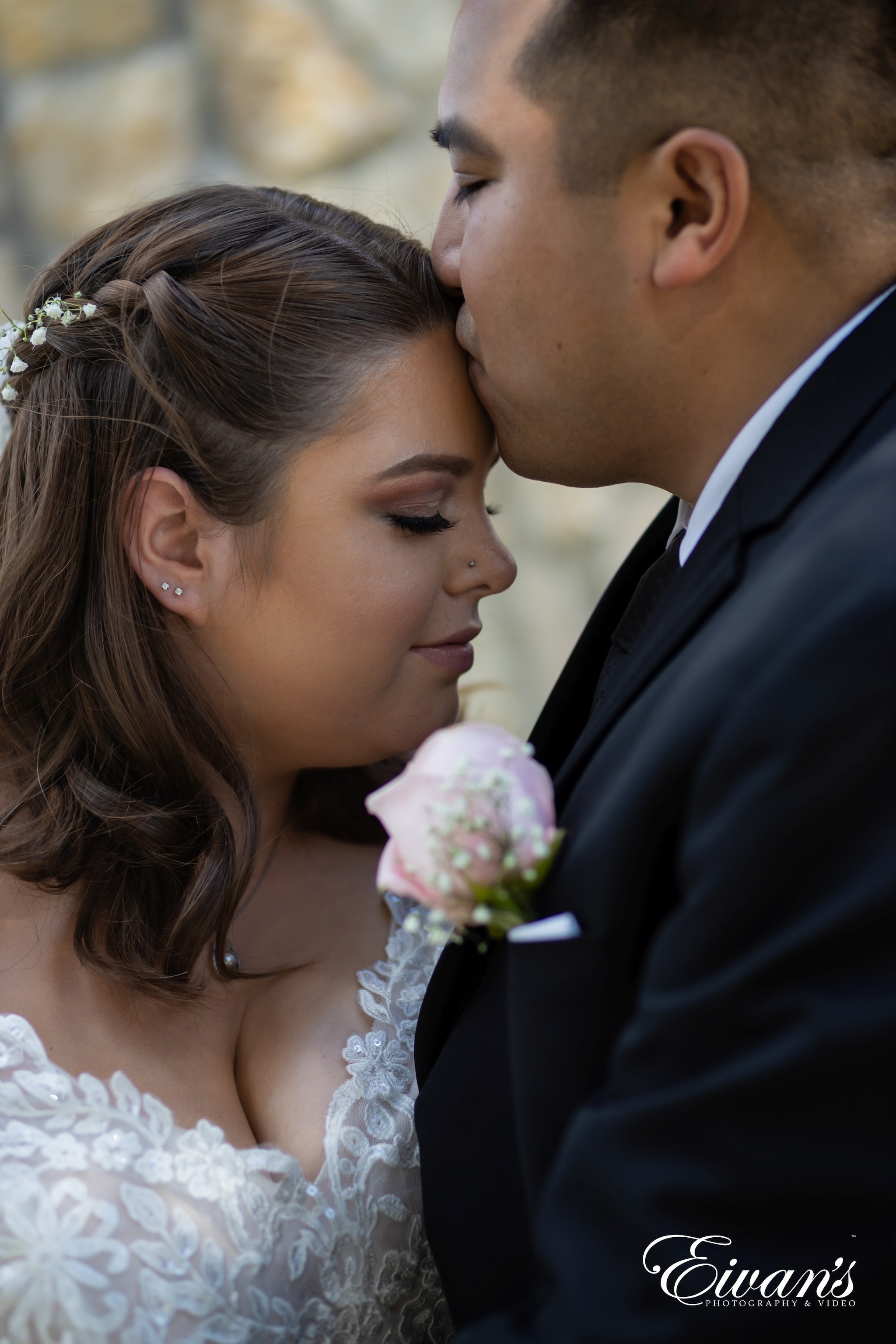 man in black suit kissing woman in white floral wedding dress