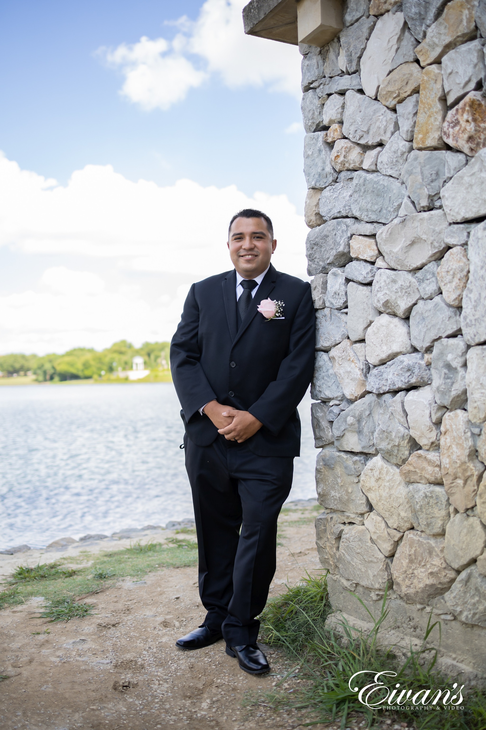man in black suit standing beside gray concrete wall during daytime