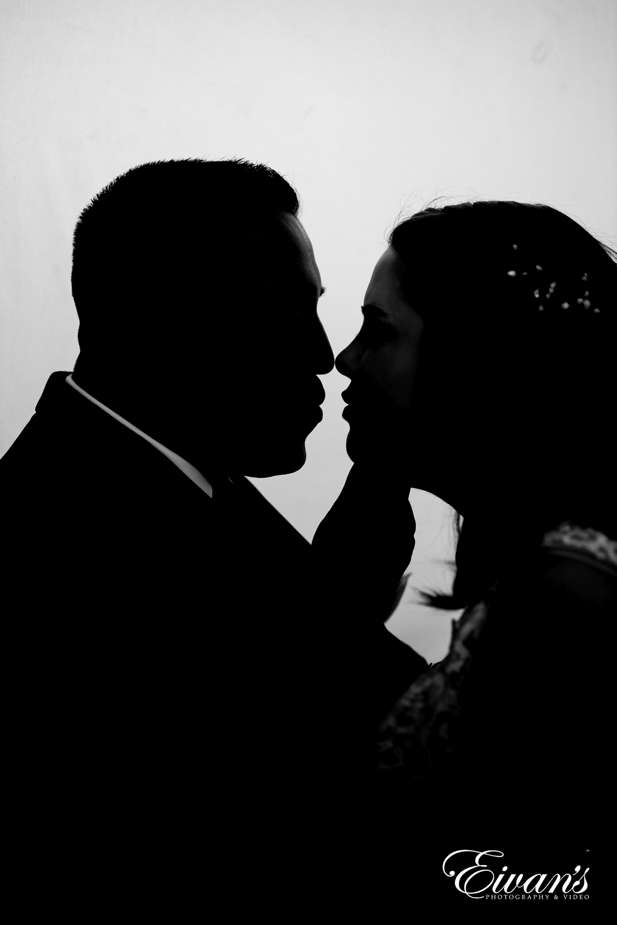 man in black suit jacket kissing woman in white and black floral dress