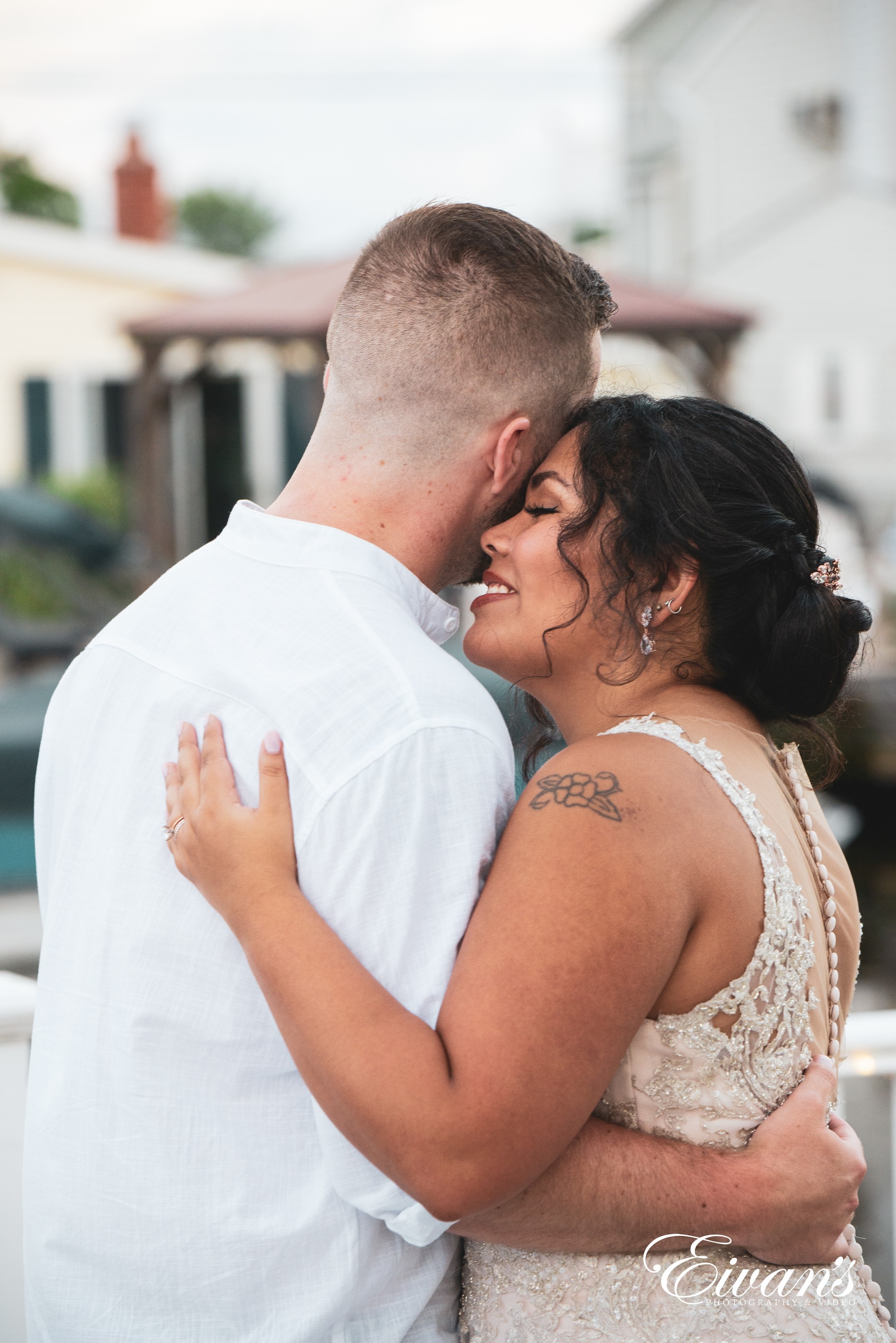 man in white dress shirt kissing woman in white sleeveless dress