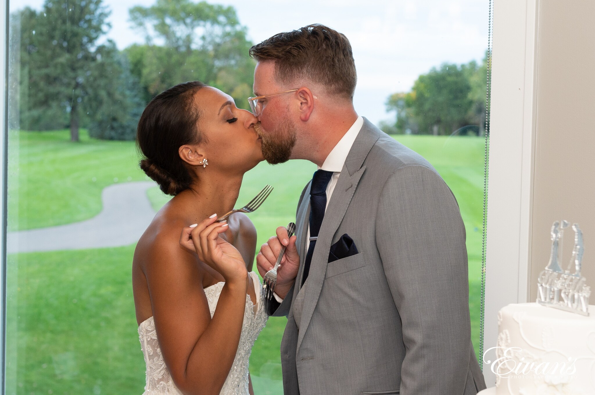 man in black suit kissing woman in white sleeveless dress