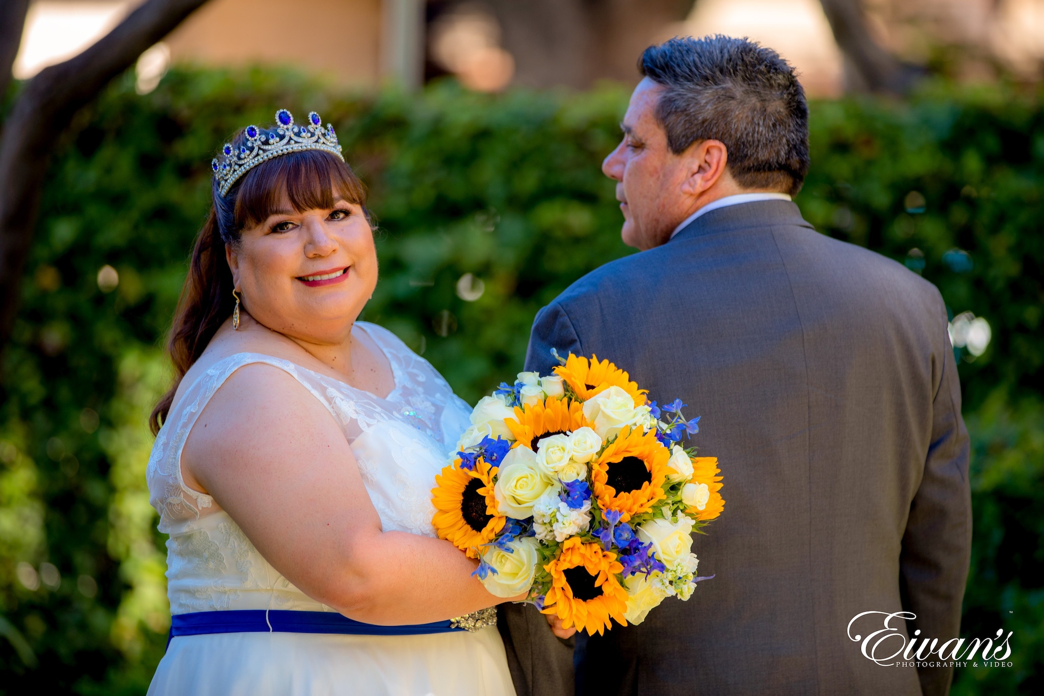 man in black suit kissing woman in white floral wedding dress