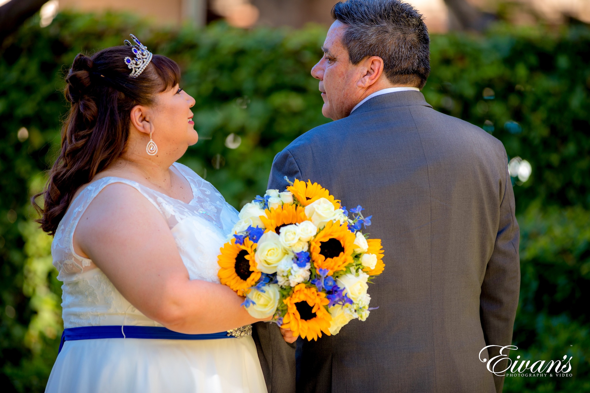 man in black suit kissing woman in white floral wedding dress