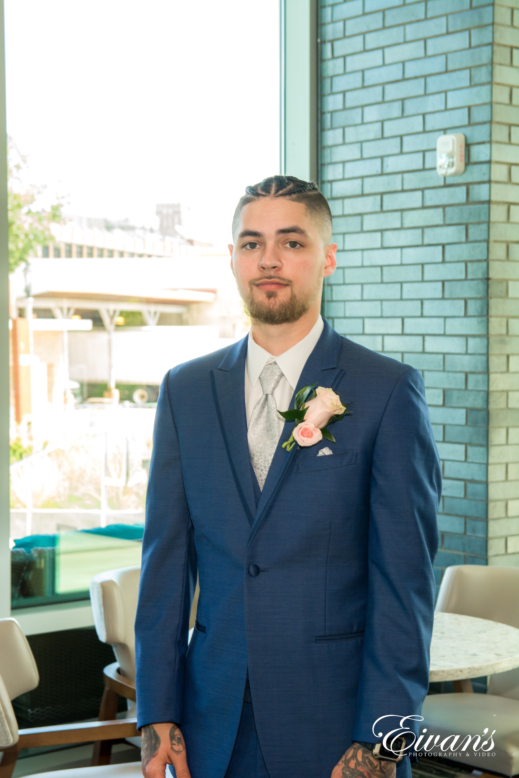 man in blue suit jacket standing near white plastic chair