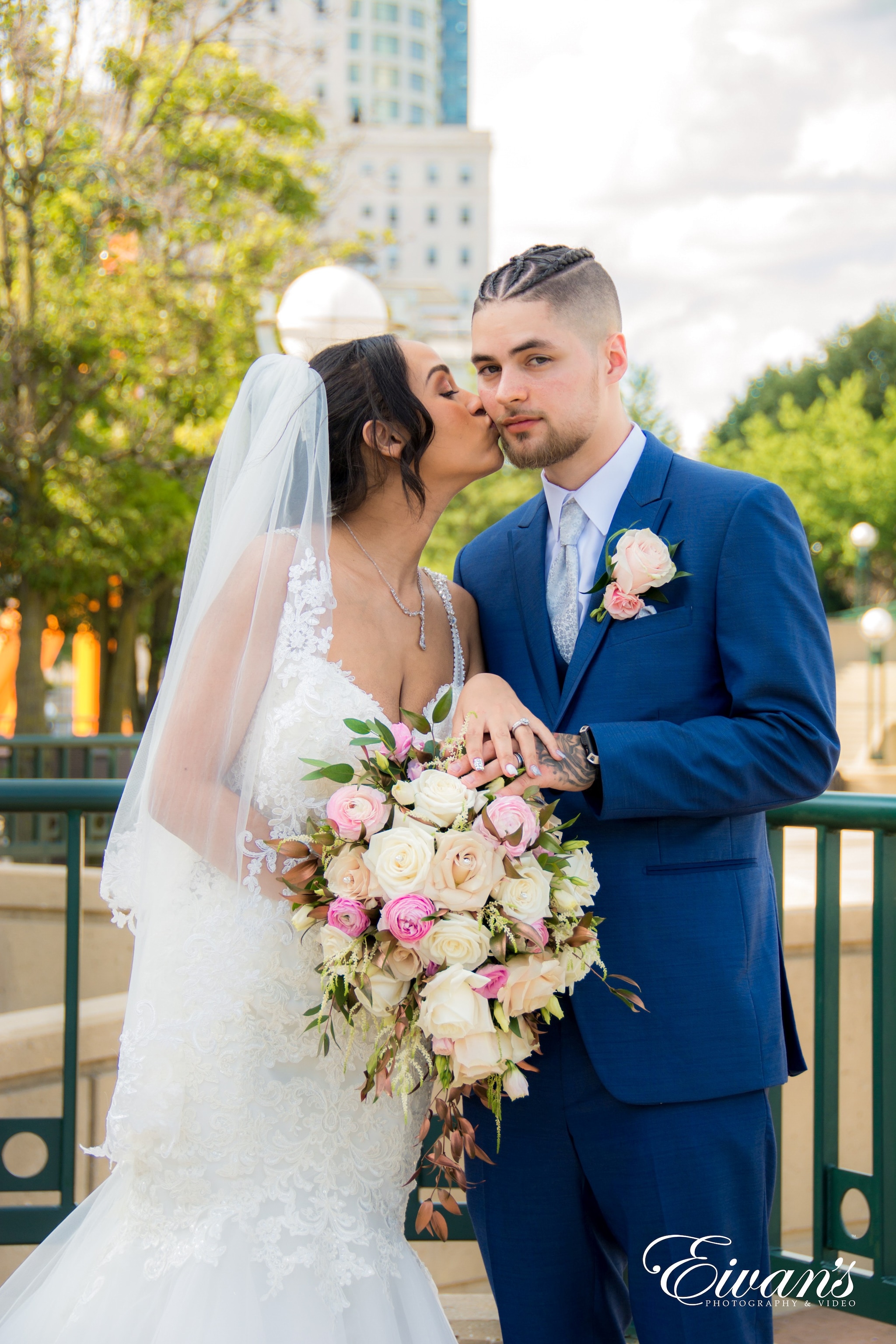 man in blue suit and woman in white wedding dress holding bouquet of flowers