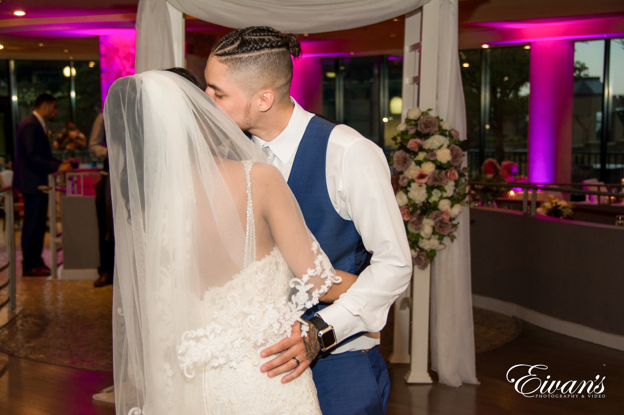man in blue vest kissing woman in white wedding dress