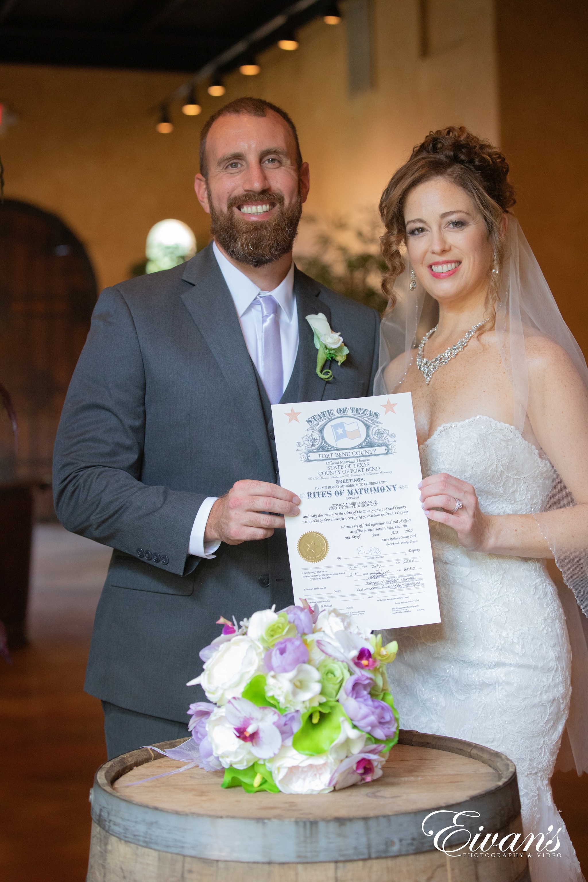 man in black suit holding woman in white wedding dress holding bouquet of flowers