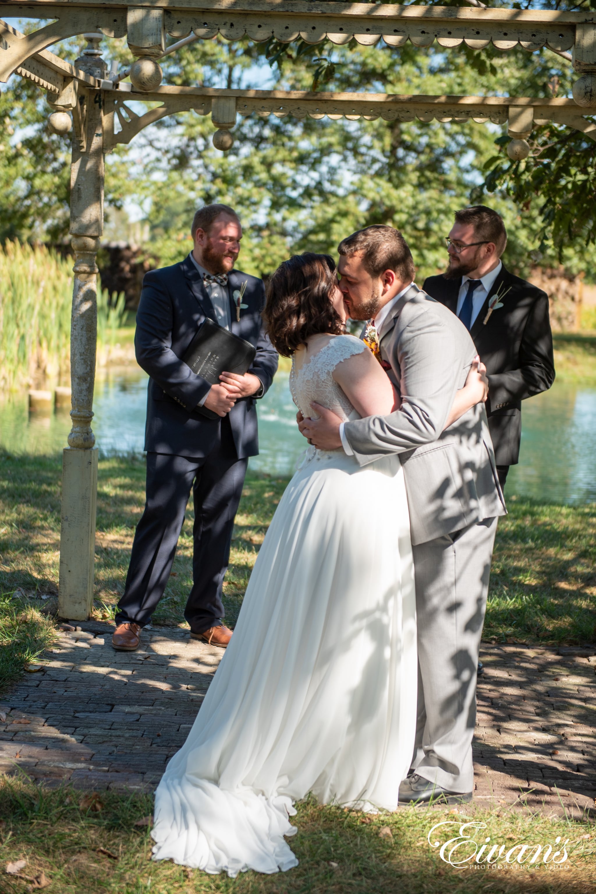 man in black suit kissing woman in white wedding dress