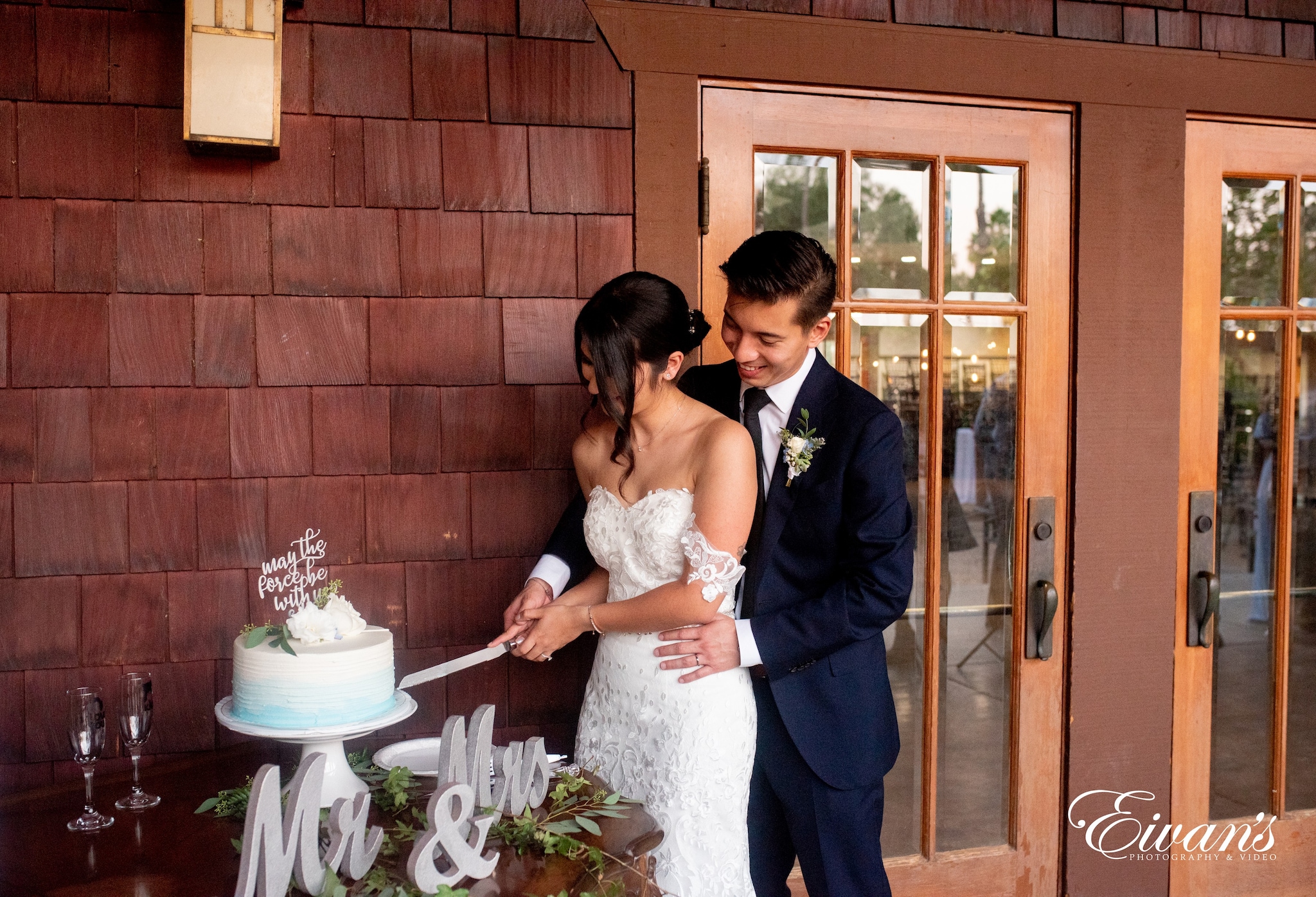 man in black suit and woman in white wedding dress cutting white cake