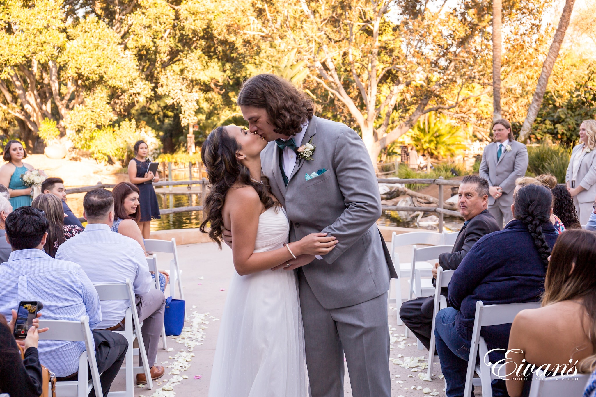 man in gray suit jacket kissing woman in white wedding dress
